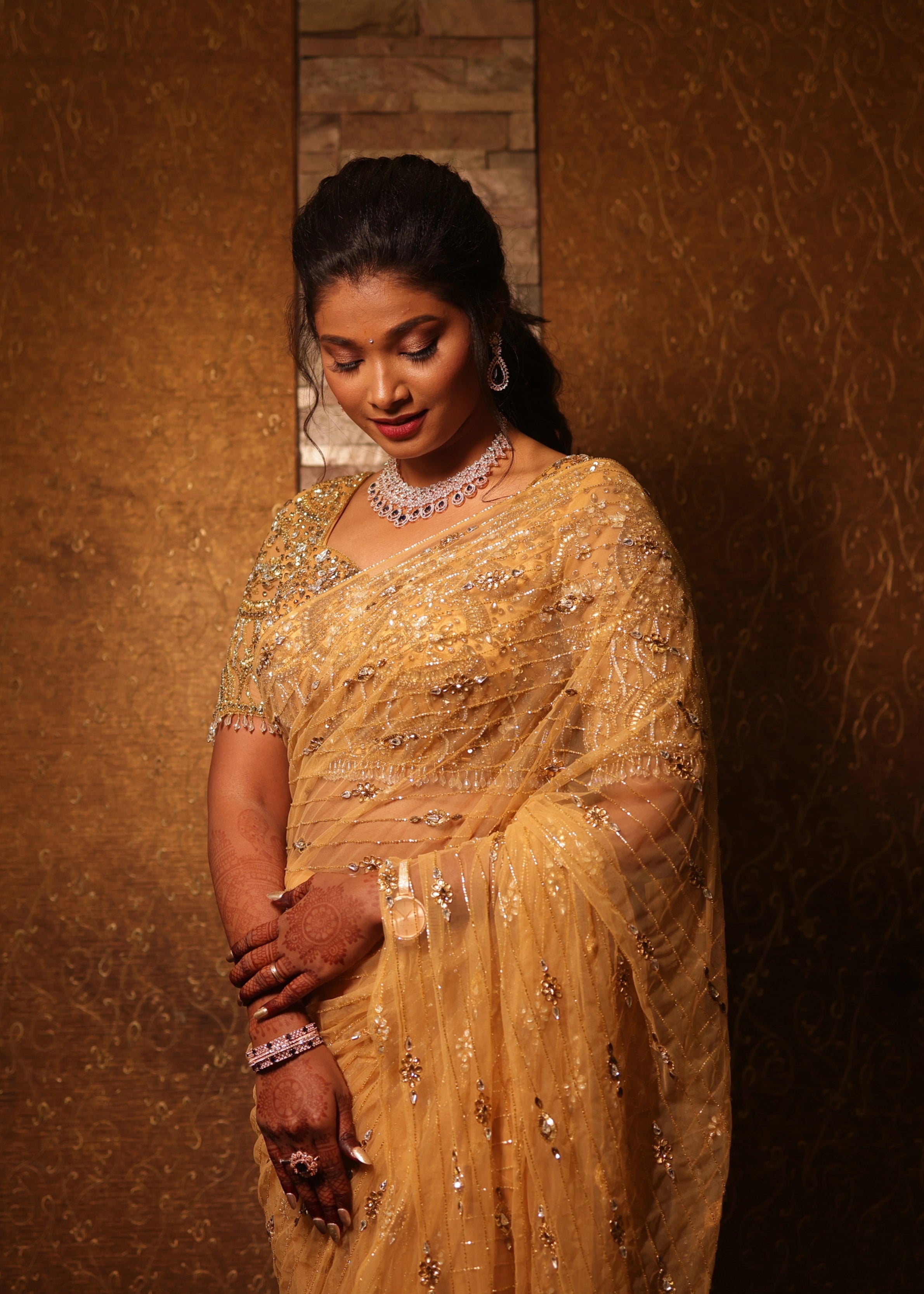 Bride from Chennai posing in a handcrafted metallic gold net saree designed by Archana Karthick with rhinestones