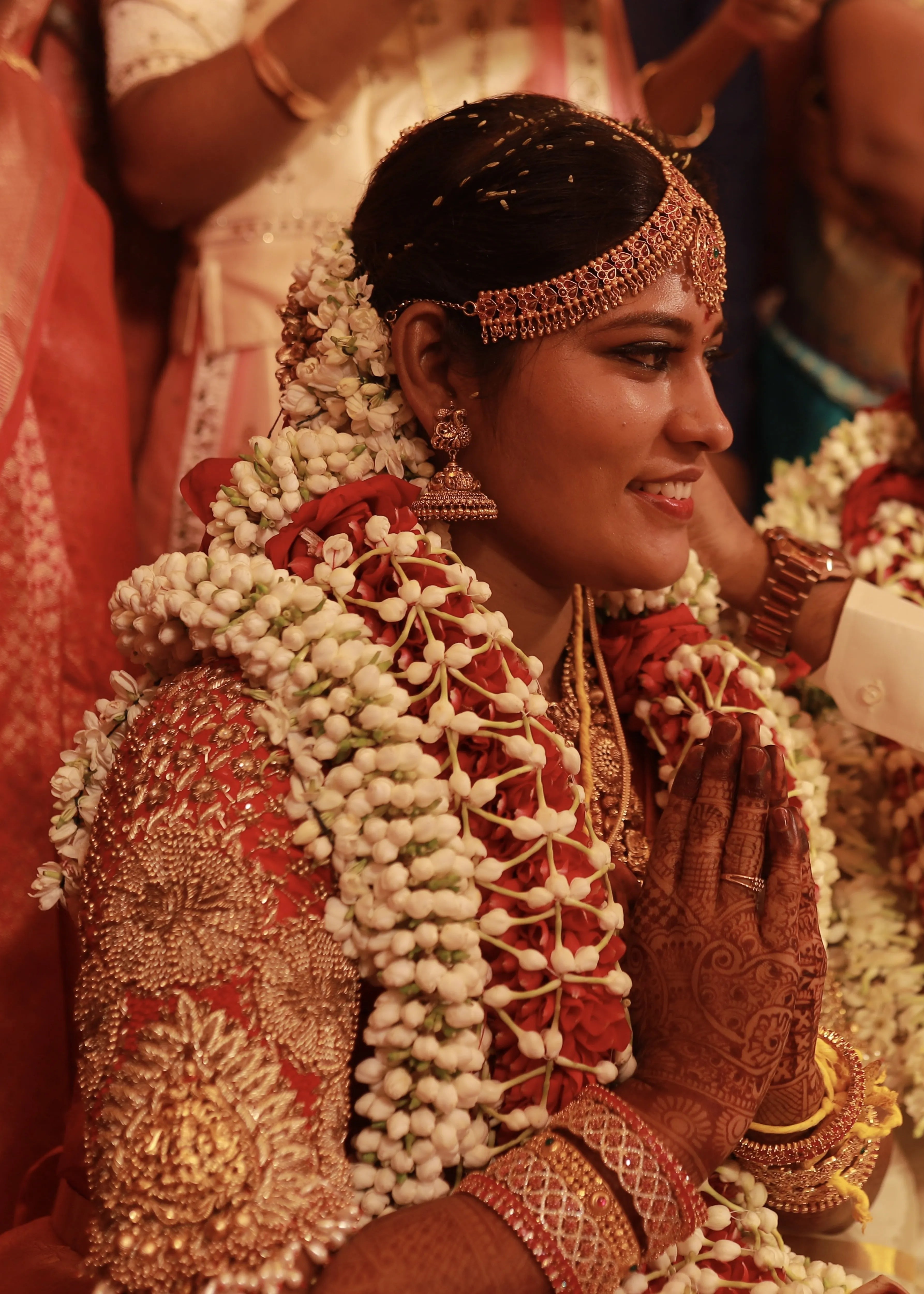 Bride from Chennai posing in a handcrafted red raw silk blouse embellished with zardozi, pearls, beads with goddess pendants on sleeves.