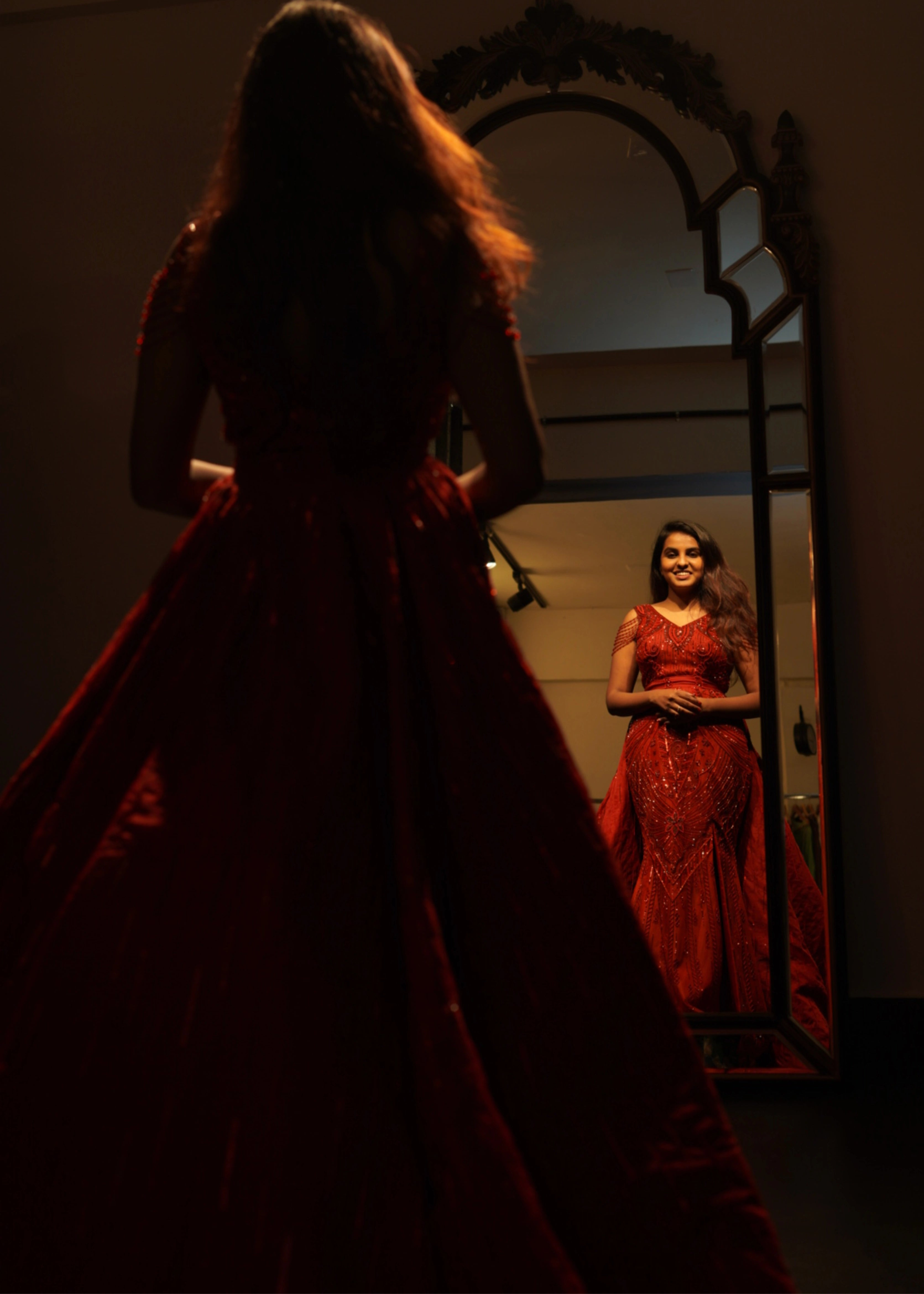 Bride from Chennai posing in a red mermaid gown with detachable trail handcrafted with rhinestones, crystal beads, cutdanas and sequins. Designed by Archana Karthick