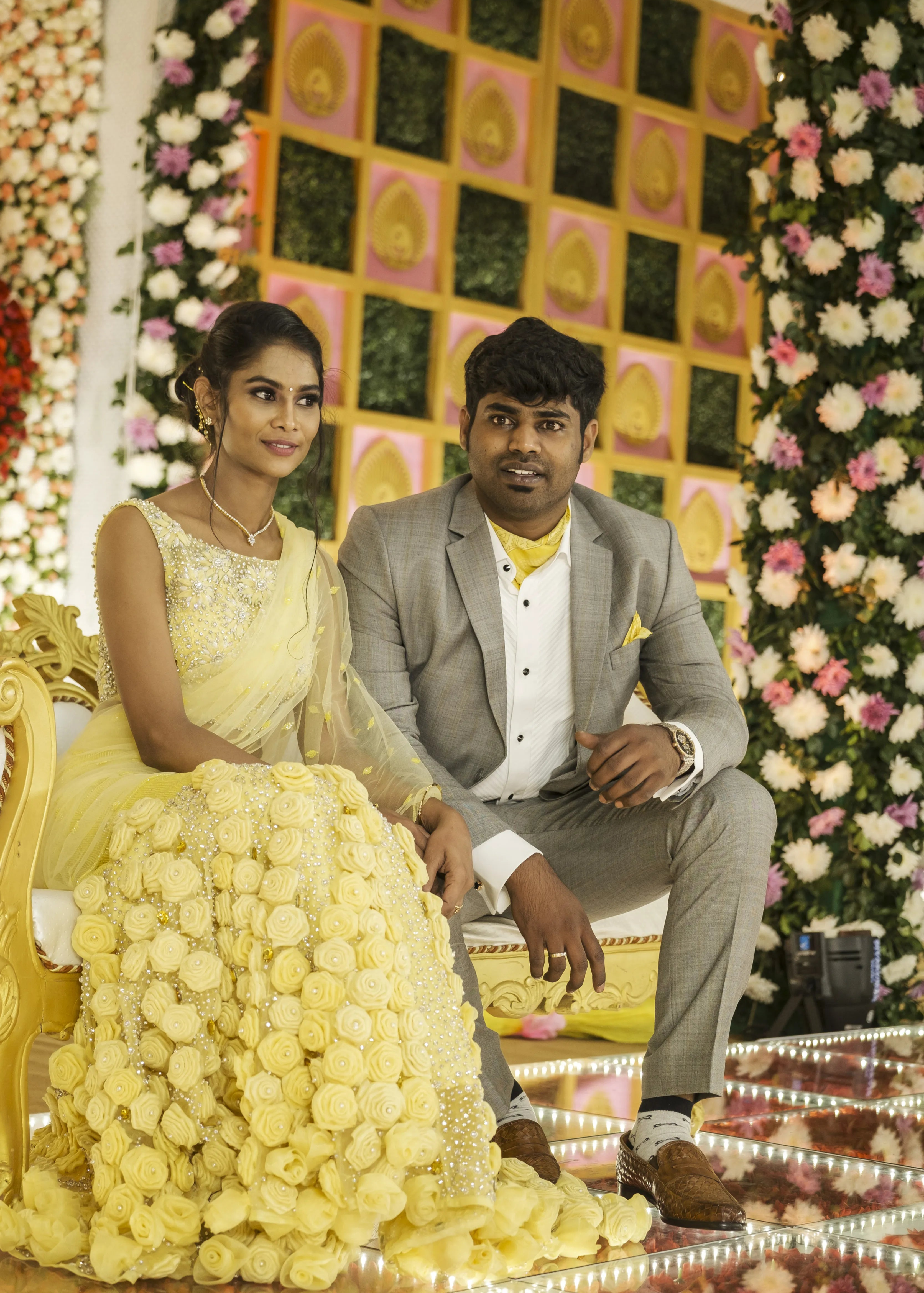 Bride from Chennai seated on stage with groom in handcrafted yellow mermaid lehenga embellished with cut dana, pearls, rhinestones and handmade 3D flowers.