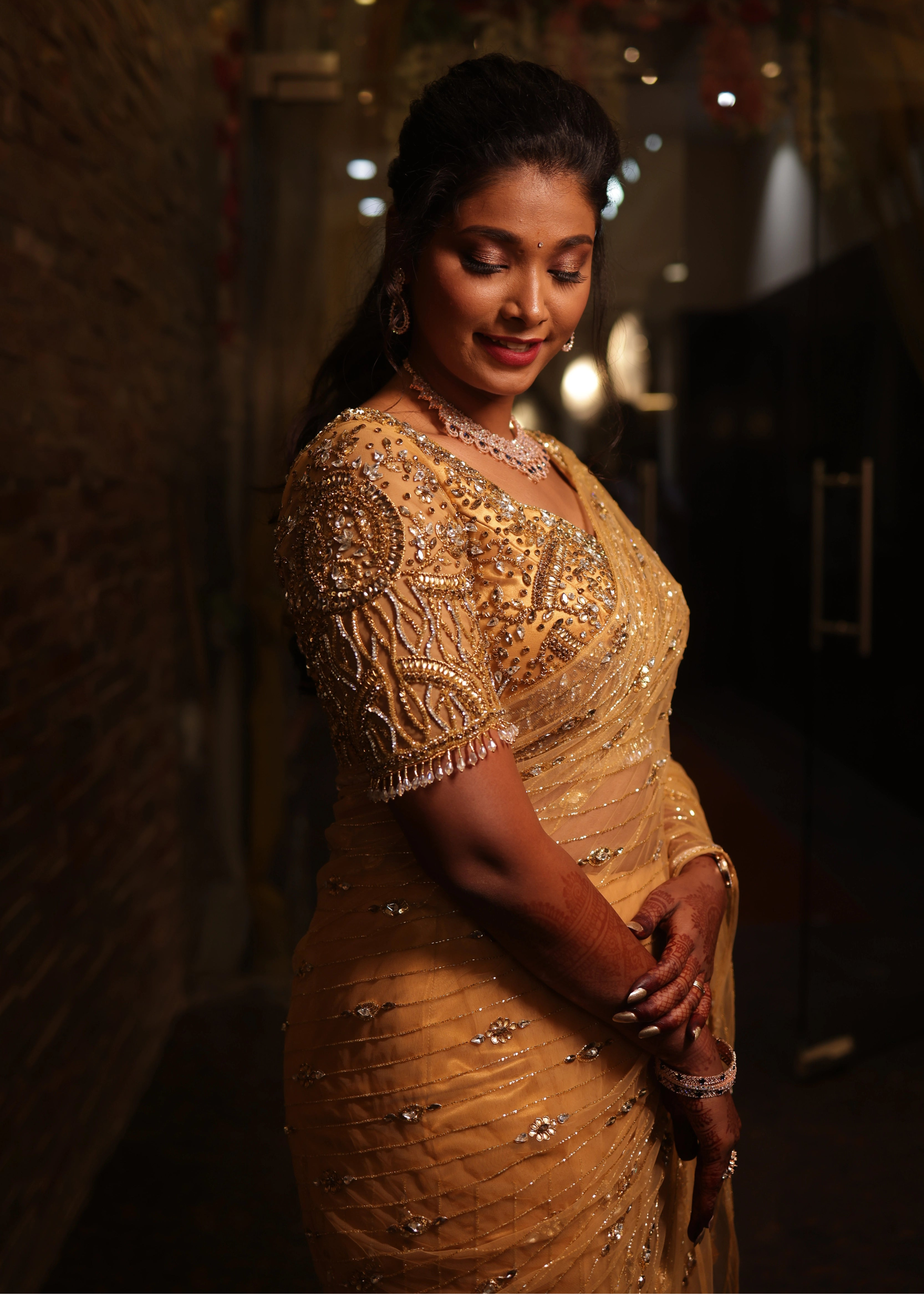 Bride from Chennai side profile posing in a handcrafted metallic gold net saree designed by Archana Karthick with rhinestones