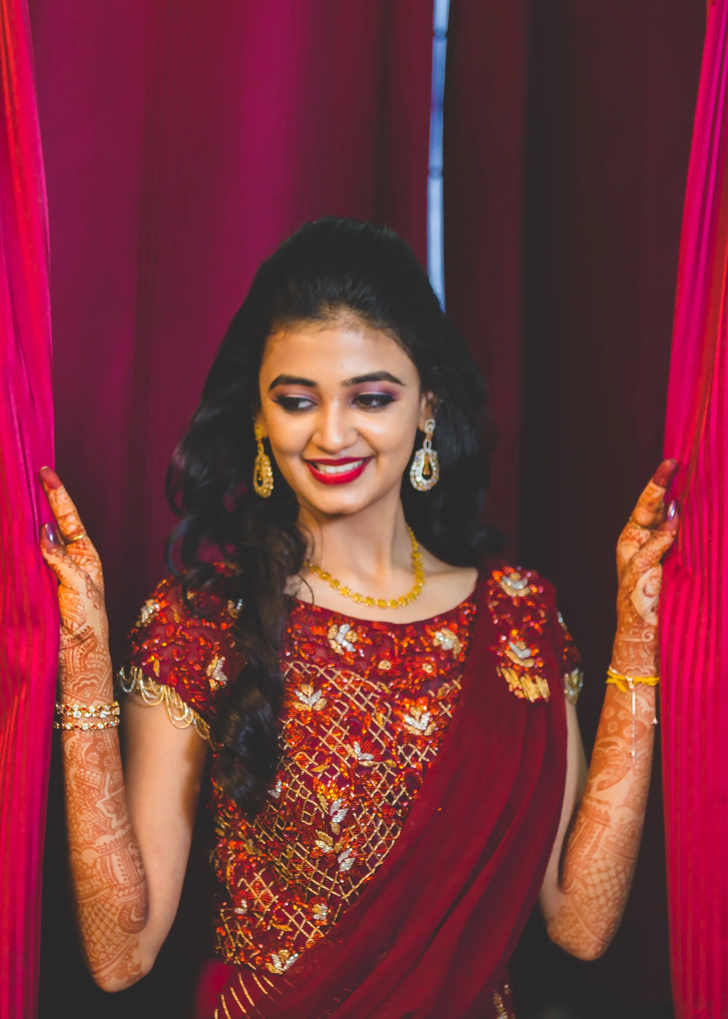 Bride from Chennai smiling in a handcrafted maroon raw silk gown with draped dupatta.