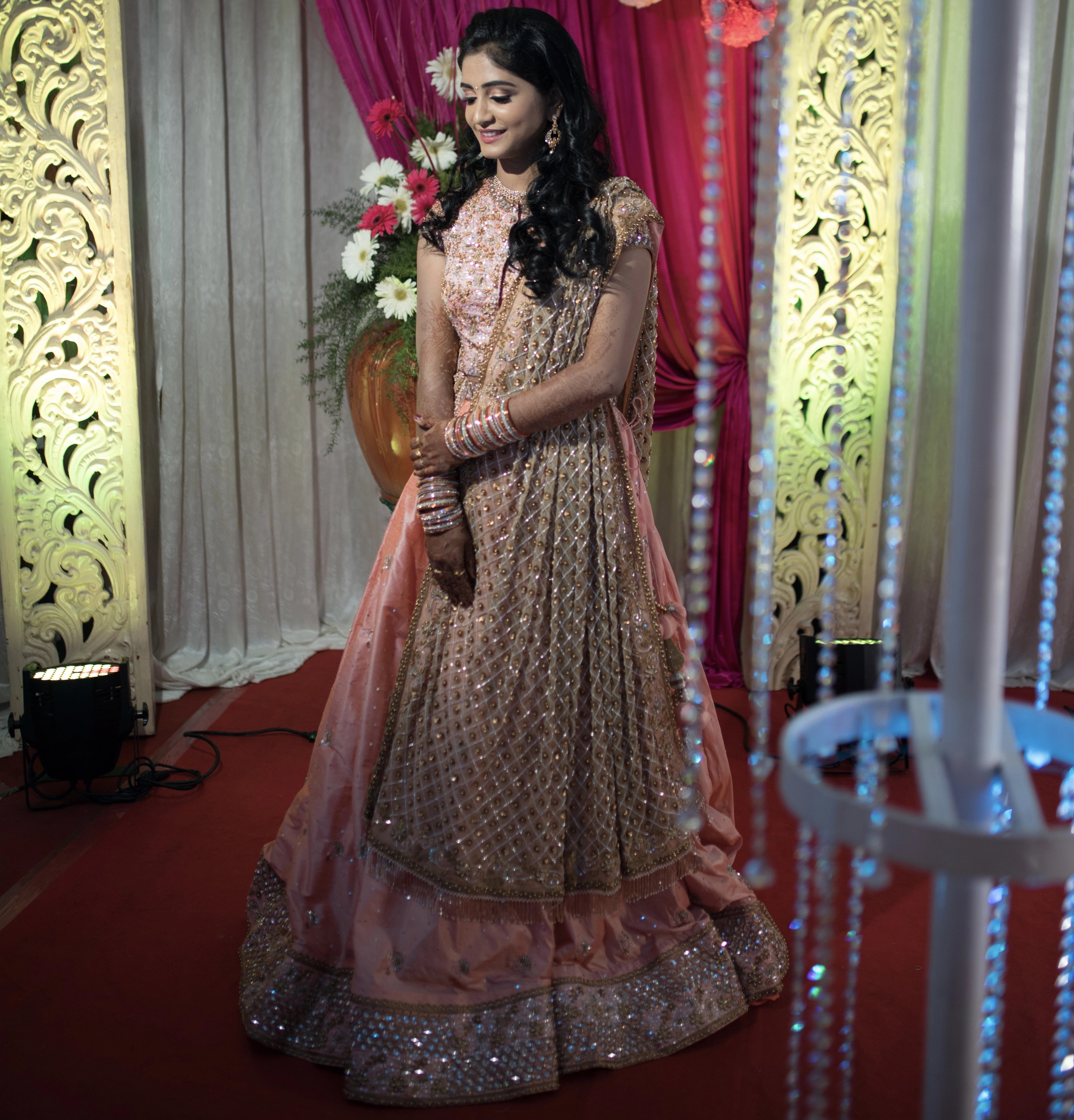 Bride from Coimbatore in a close up in a peach raw silk lehenga and tulle dupatta handcrafted intricately with beads, sequins, and cutdana by team Archana Karthick.