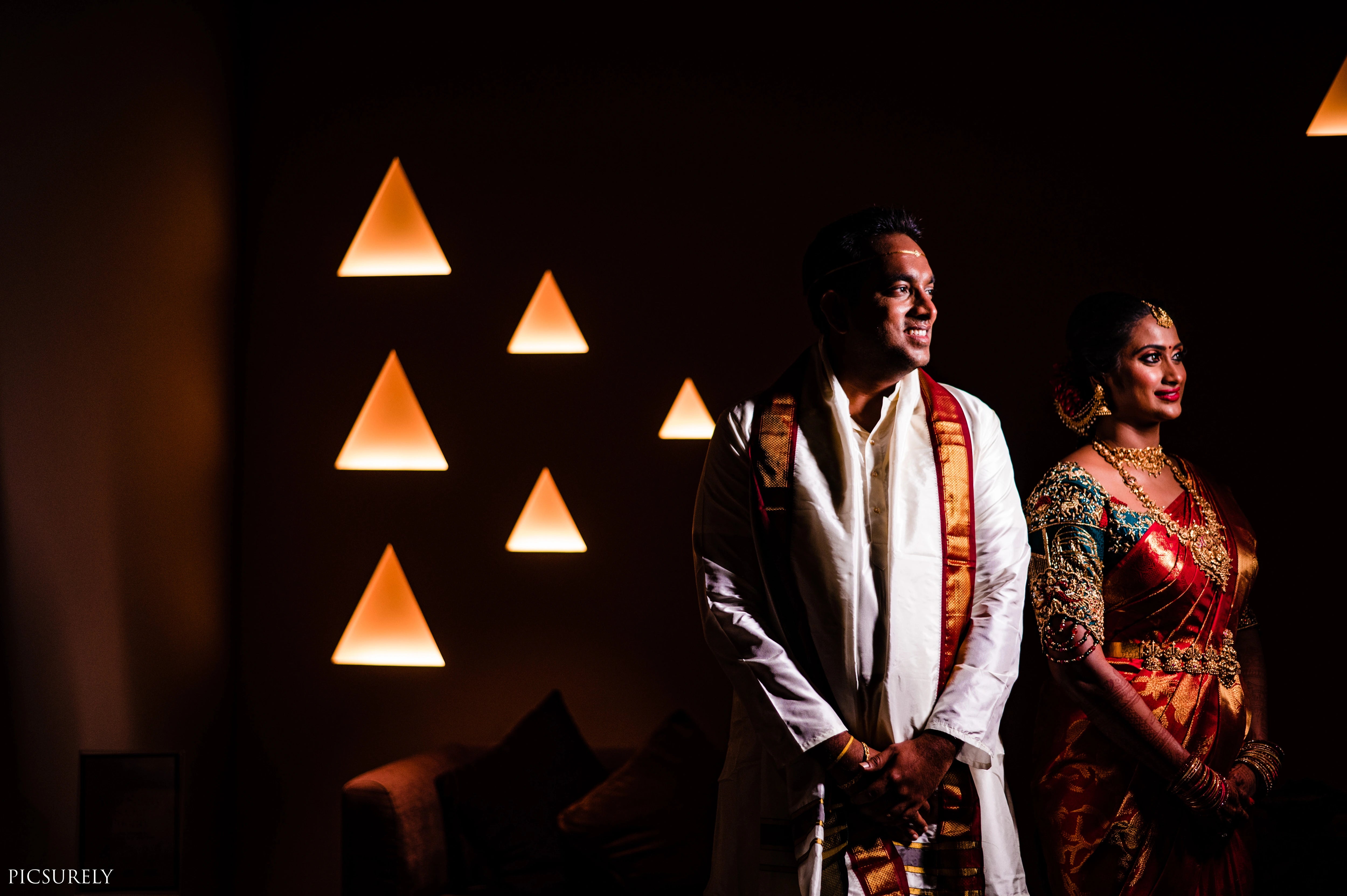 Bride from USA posing with groom in a bottle green raw silk concept blouse for her wedding, handcrafted with zardozi, stones, beads, resham work and kundan by Archana Karthick.