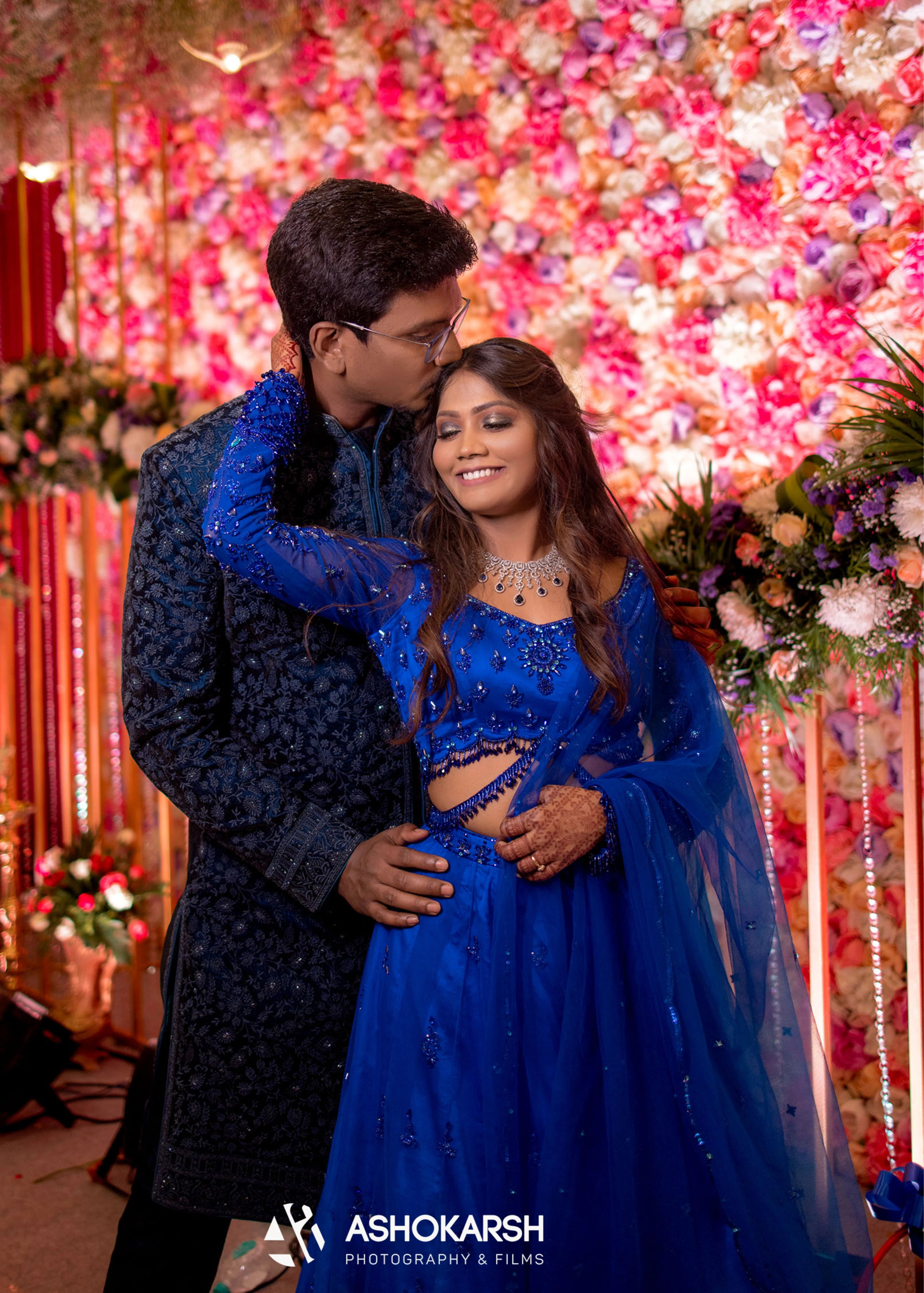 Bride from USA with groom in an embrace in a concept blue lehenga handcrafted intricately with rhinestones, crystal beads, cutdanas and sequins.