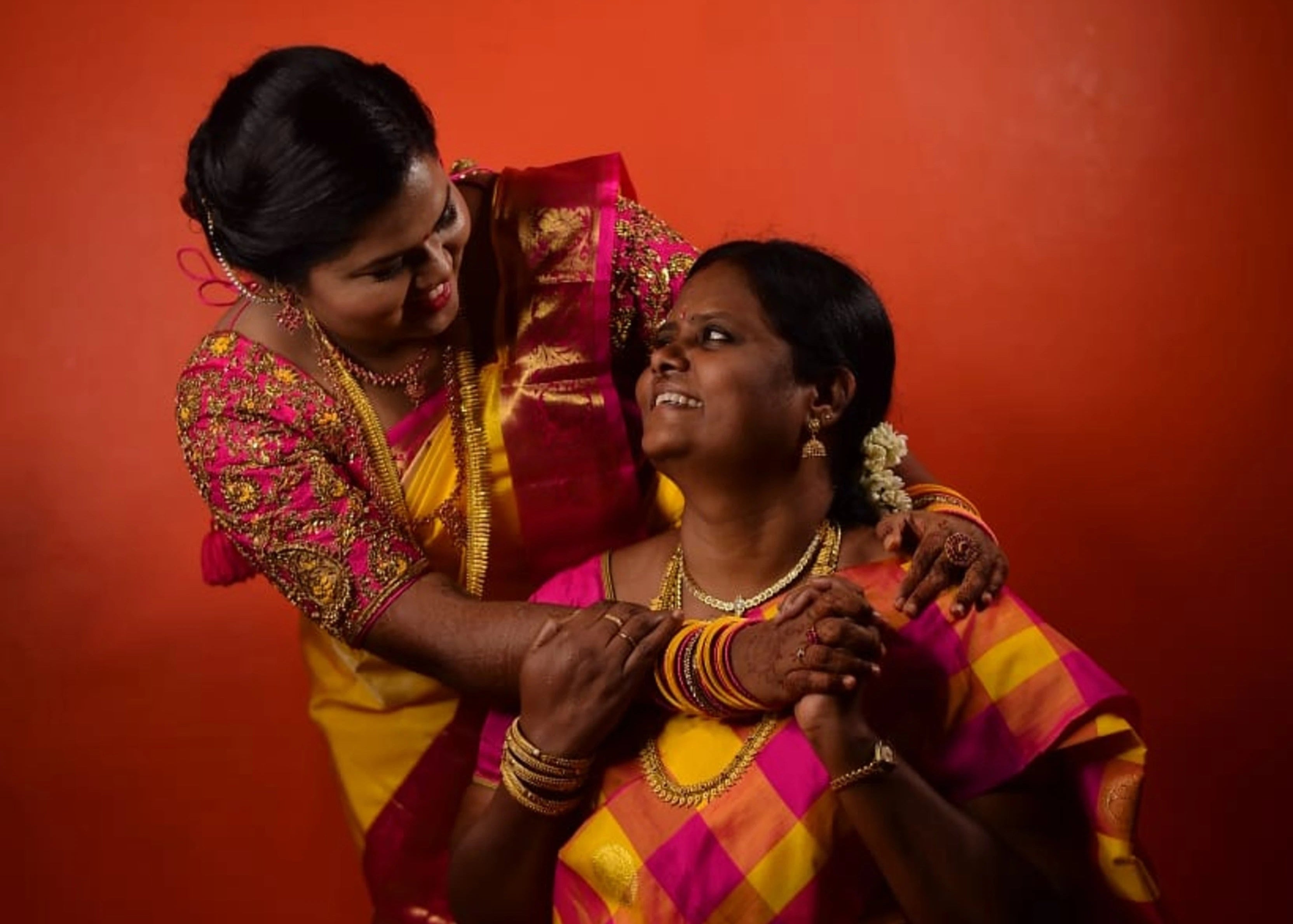 Bride posing with her mother in handcrafted pink raw silk blouse with beads, kundan, zardozi and resham knot work with paisley motifs designed by Archana Karthick