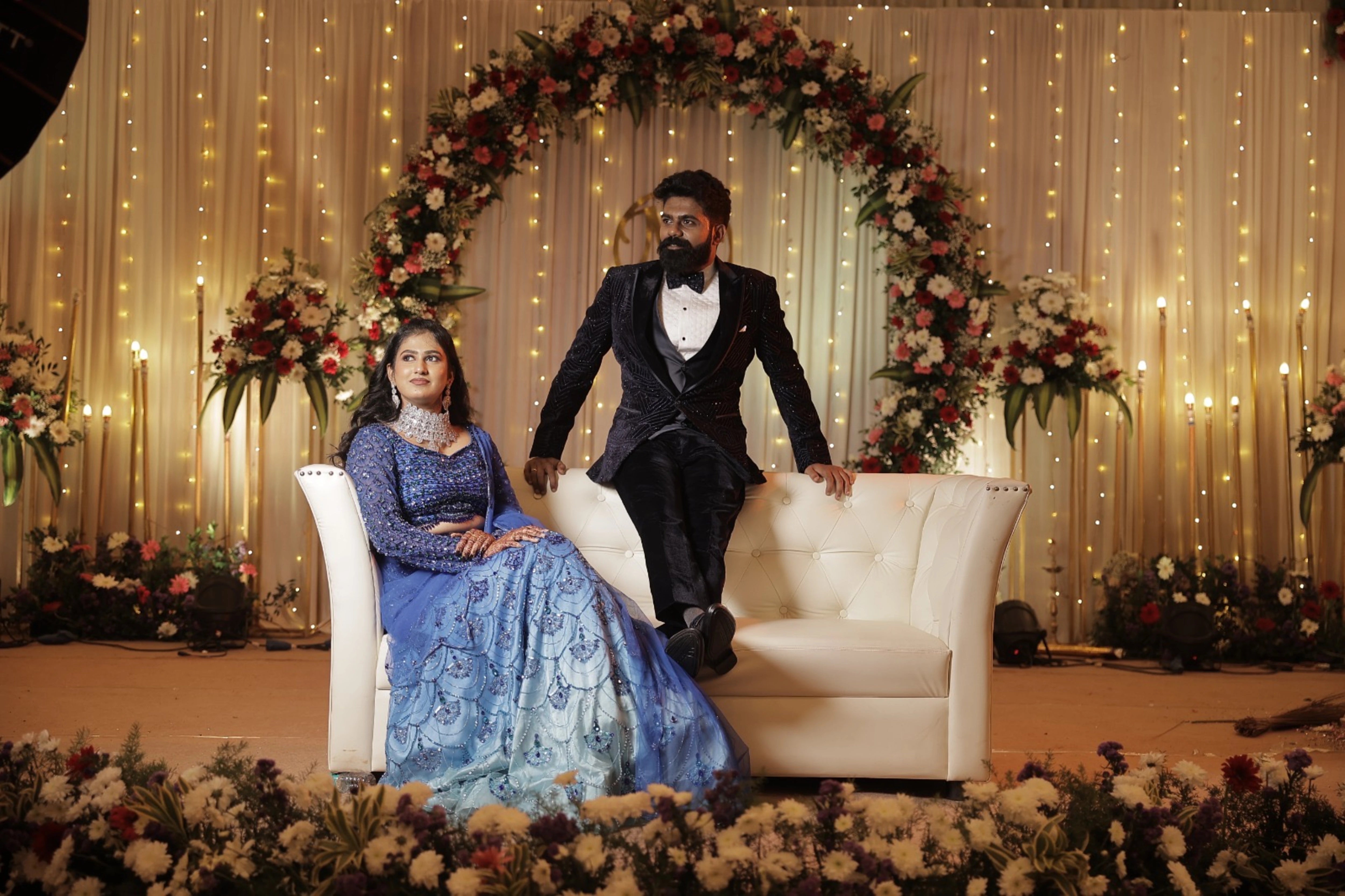 Bride Monishka smiling with groom in a peacock themed blue ombre tulle lehenga, handcrafted with sequins, cutdana, rhinestones and feathers by team Archana Karthick.