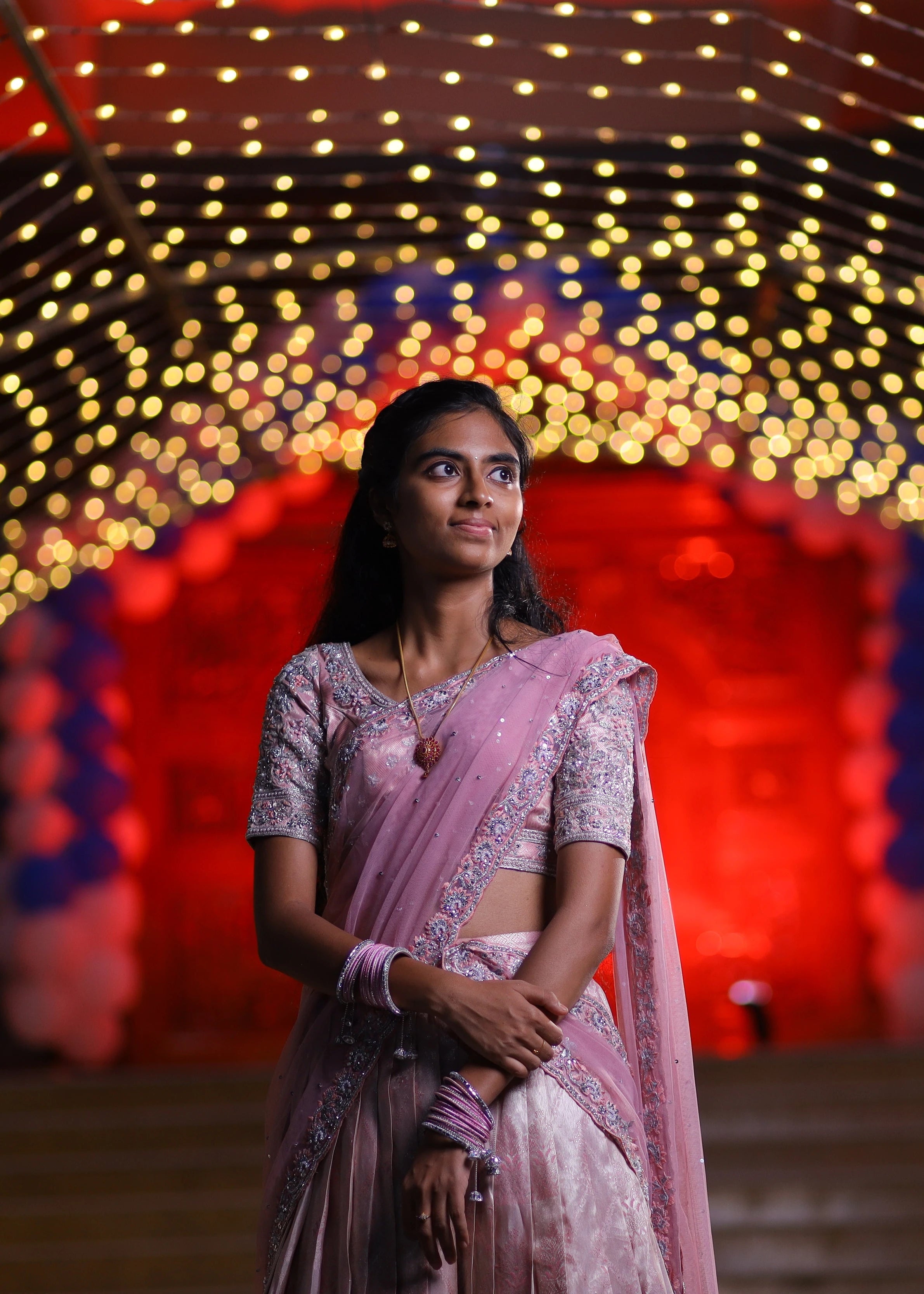 Bridesmaid Nirupama posing in an onion pink half saree, handcrafted by team Archana Karthick.