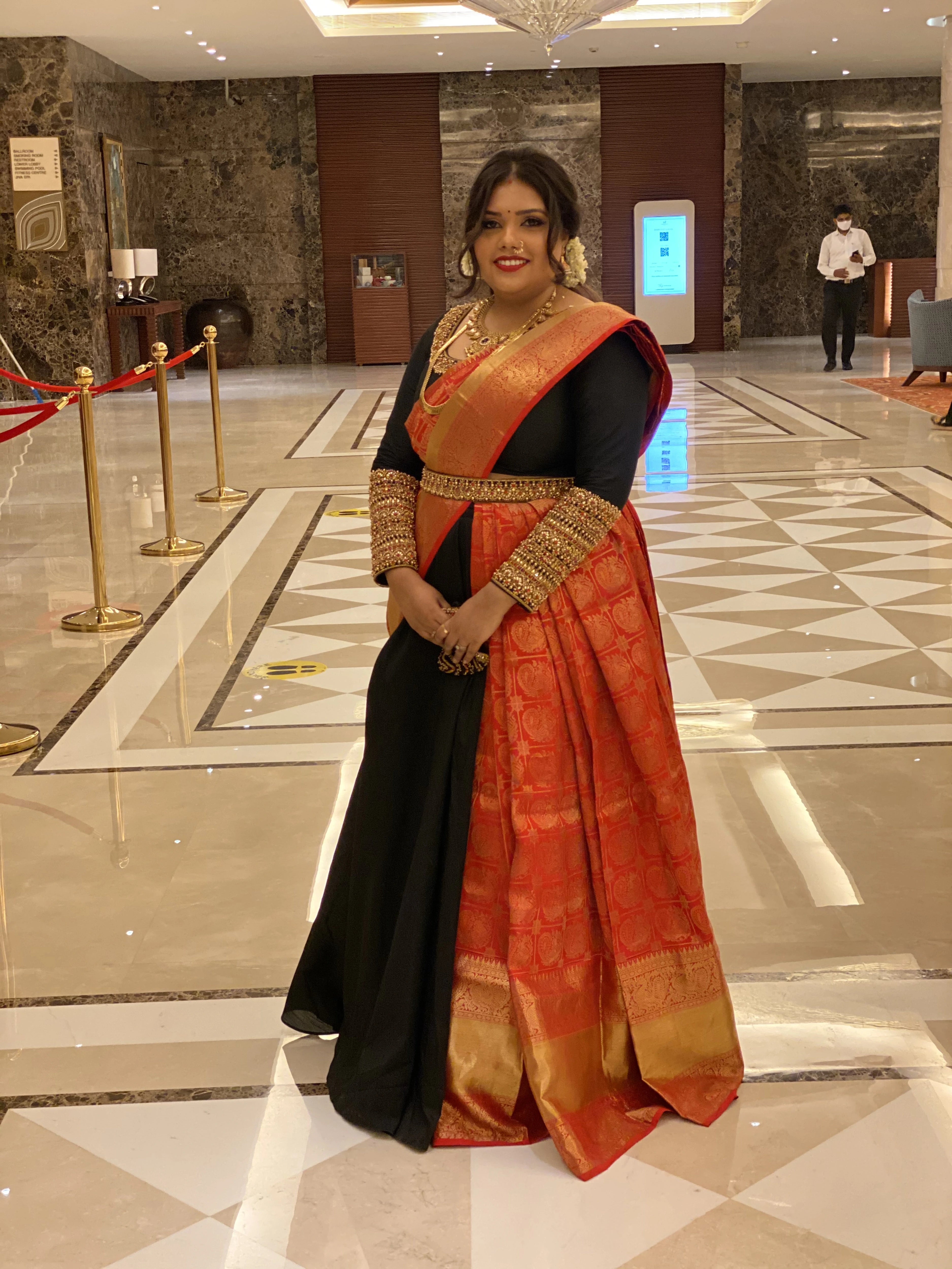Bridesmaid Nishitha in a black and burnt orange half saree, handcrafted with kemp stones, sequins, beads, zardozi and kundan by team Archana Karthick.