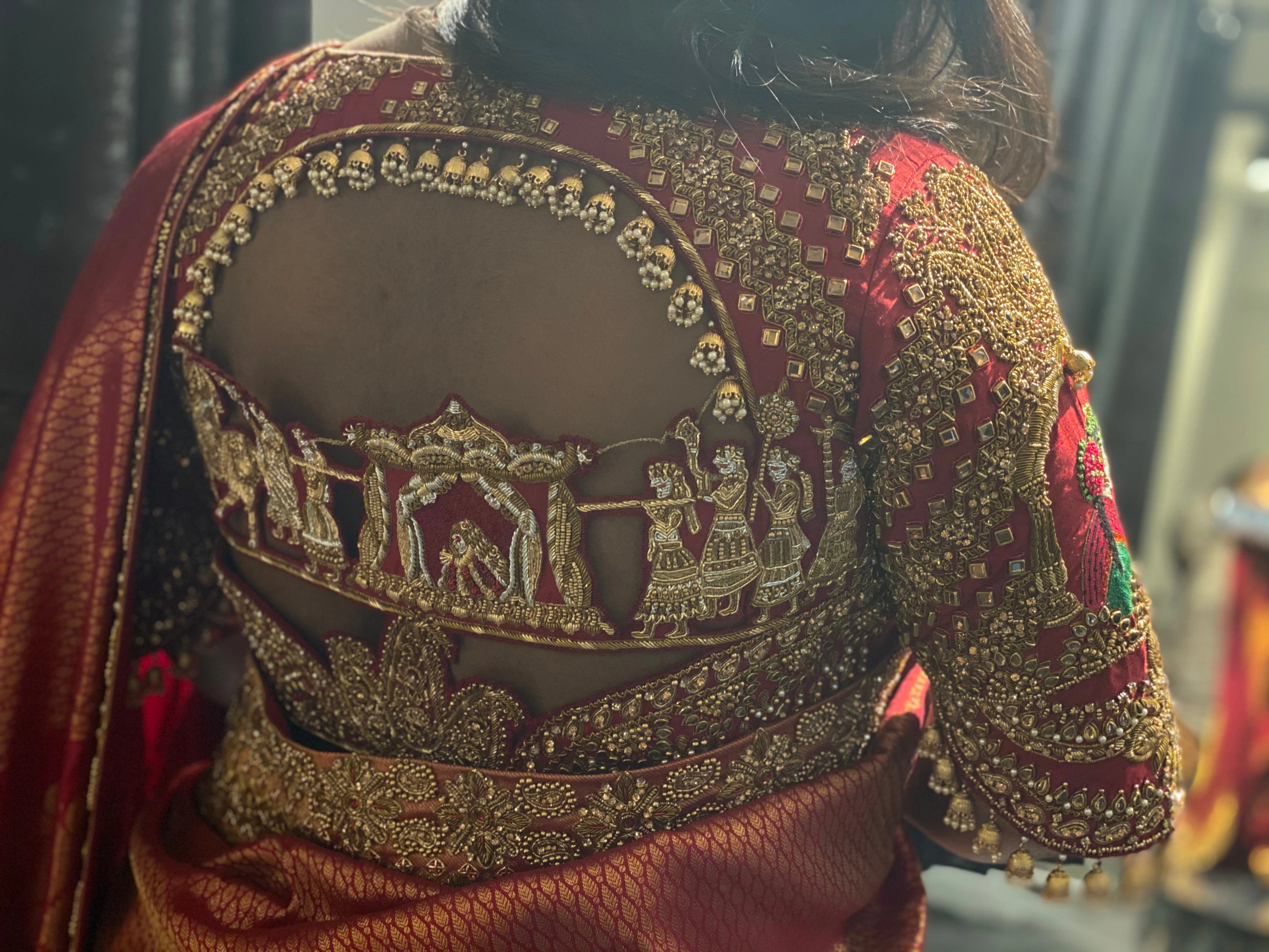 Bridesmaid Ramadevi during fittings in a red silk blouse, handcrafted by team Archana Karthick.