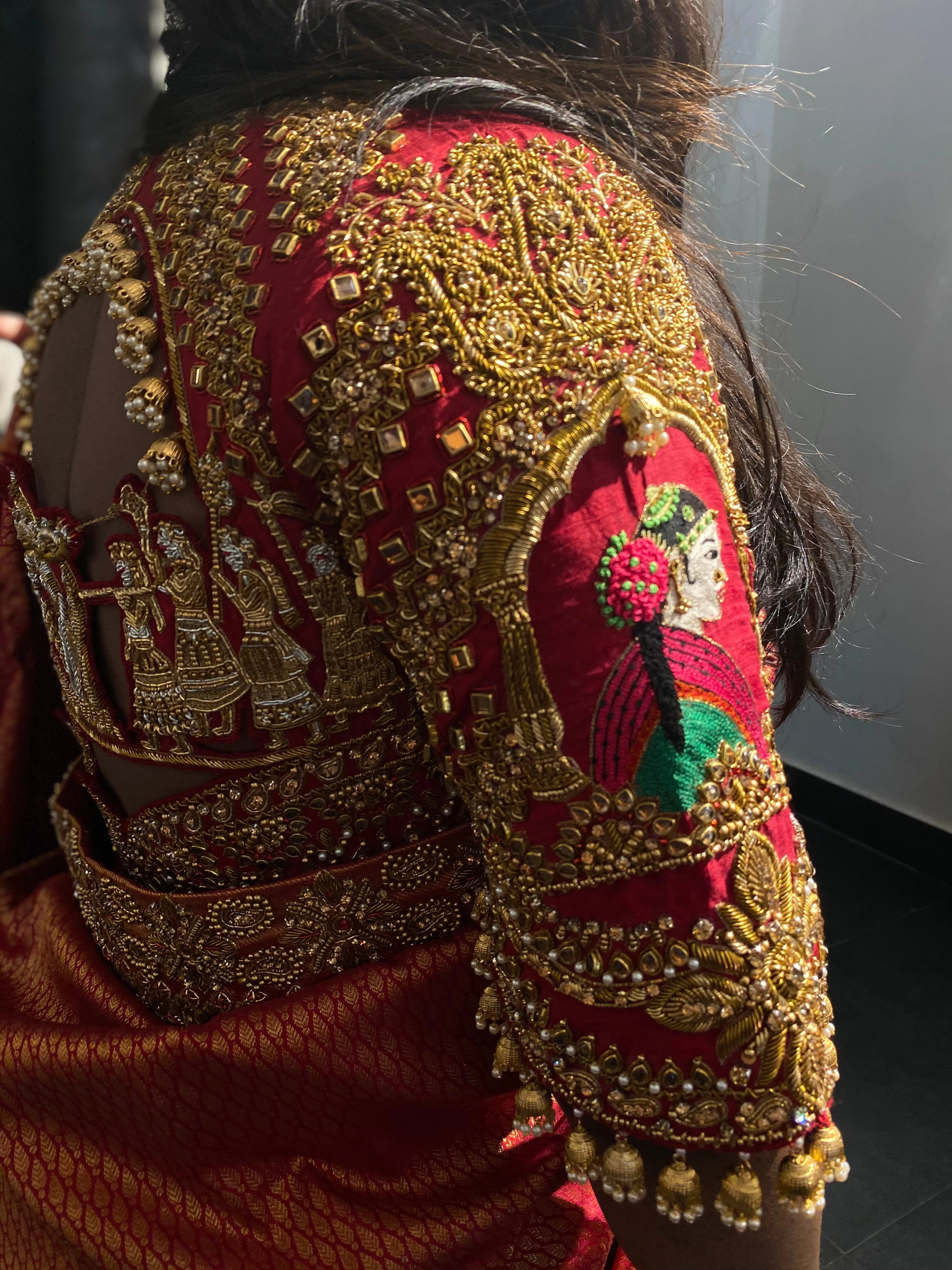 Bridesmaid Ramadevi in a red silk blouse, handcrafted by team Archana Karthick.