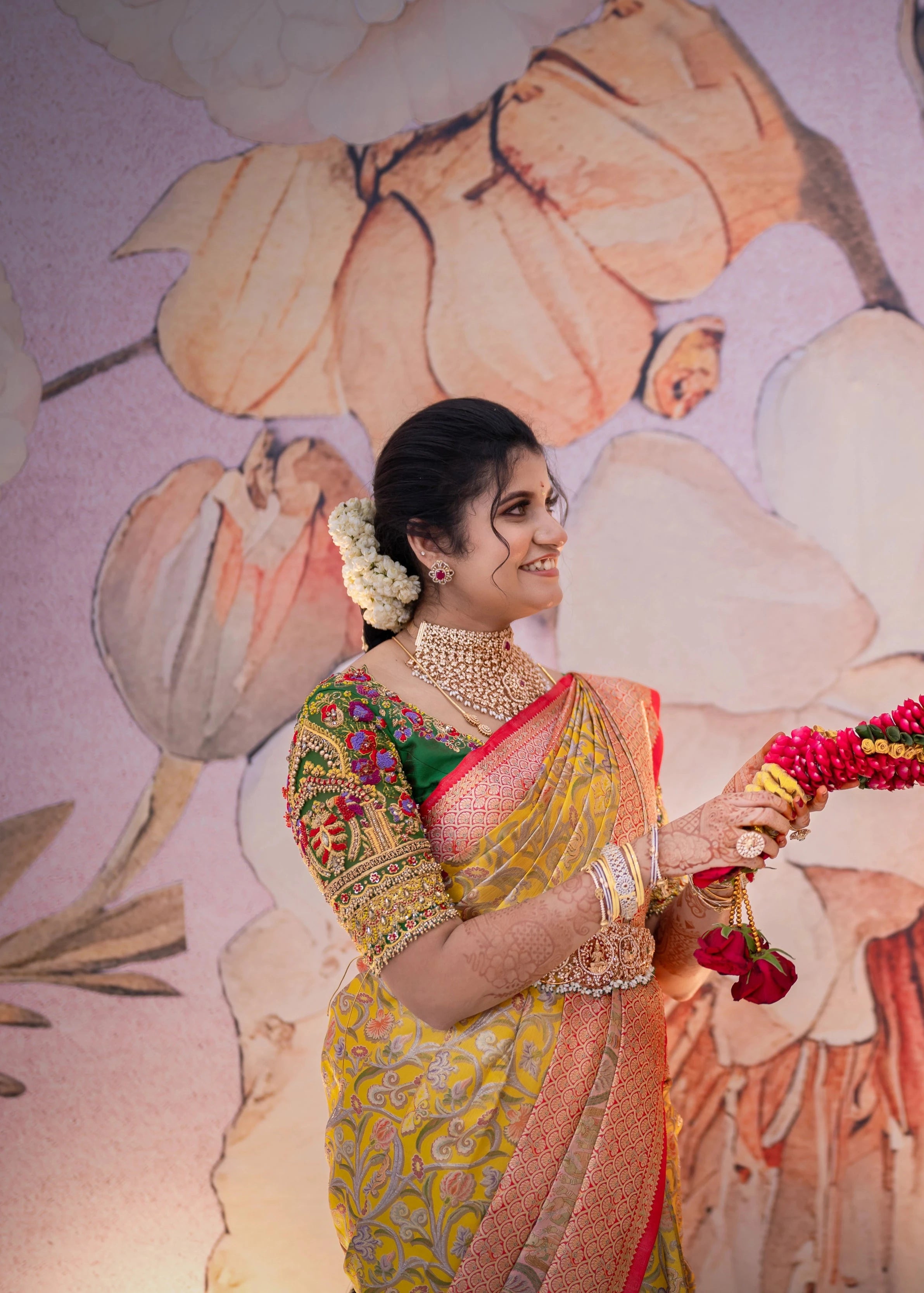 Bridesmaid Sanjana Sujith smiling in a green silk blouse intricately handcrafted with resham, zardozi, sequins, beads, crystals and stones by Archana Karthick.