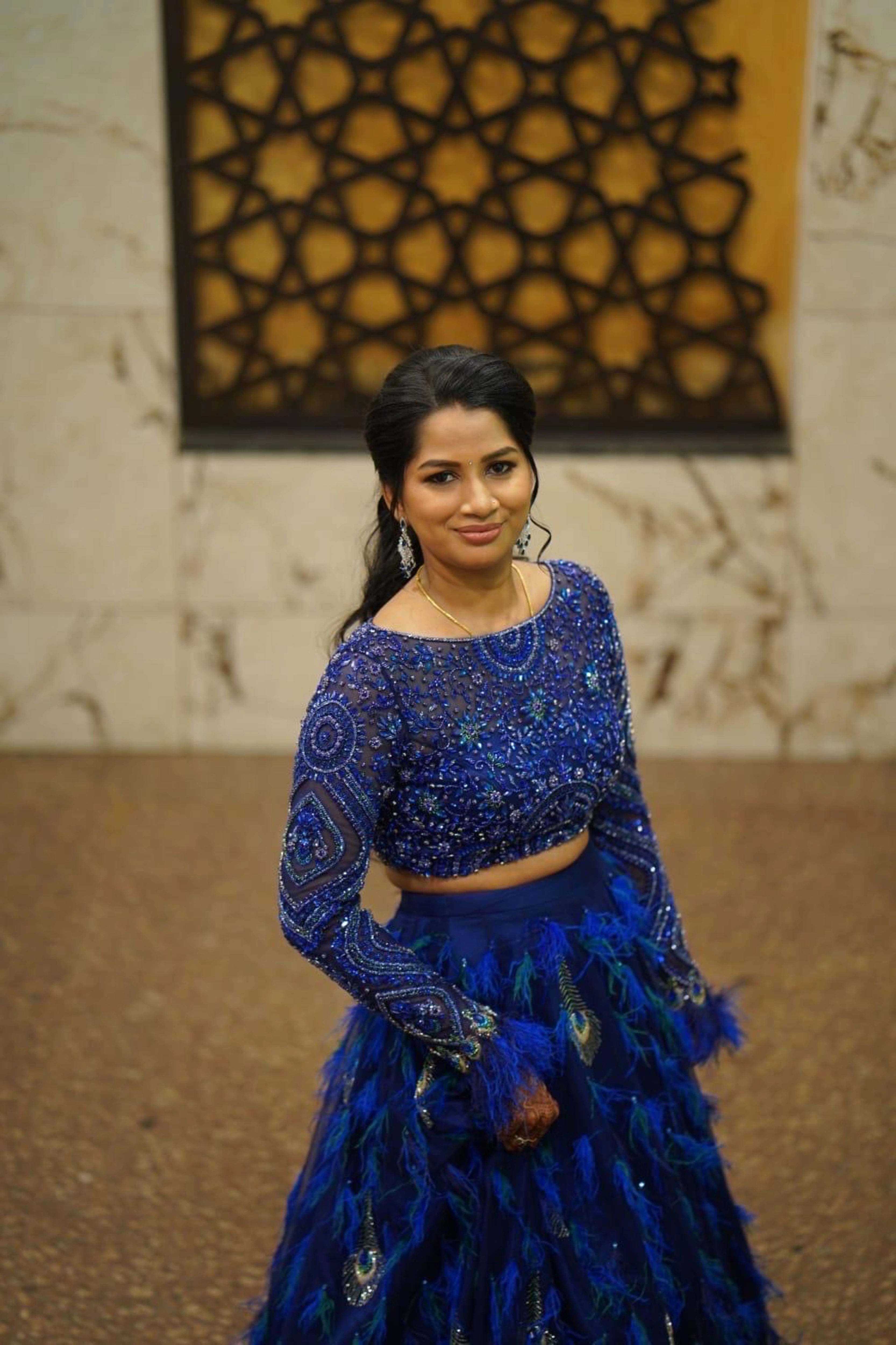 Bridesmaid Sowmiya Rajeev from Singapore, smiling in a peacock lehenga by team Archana Karthick
