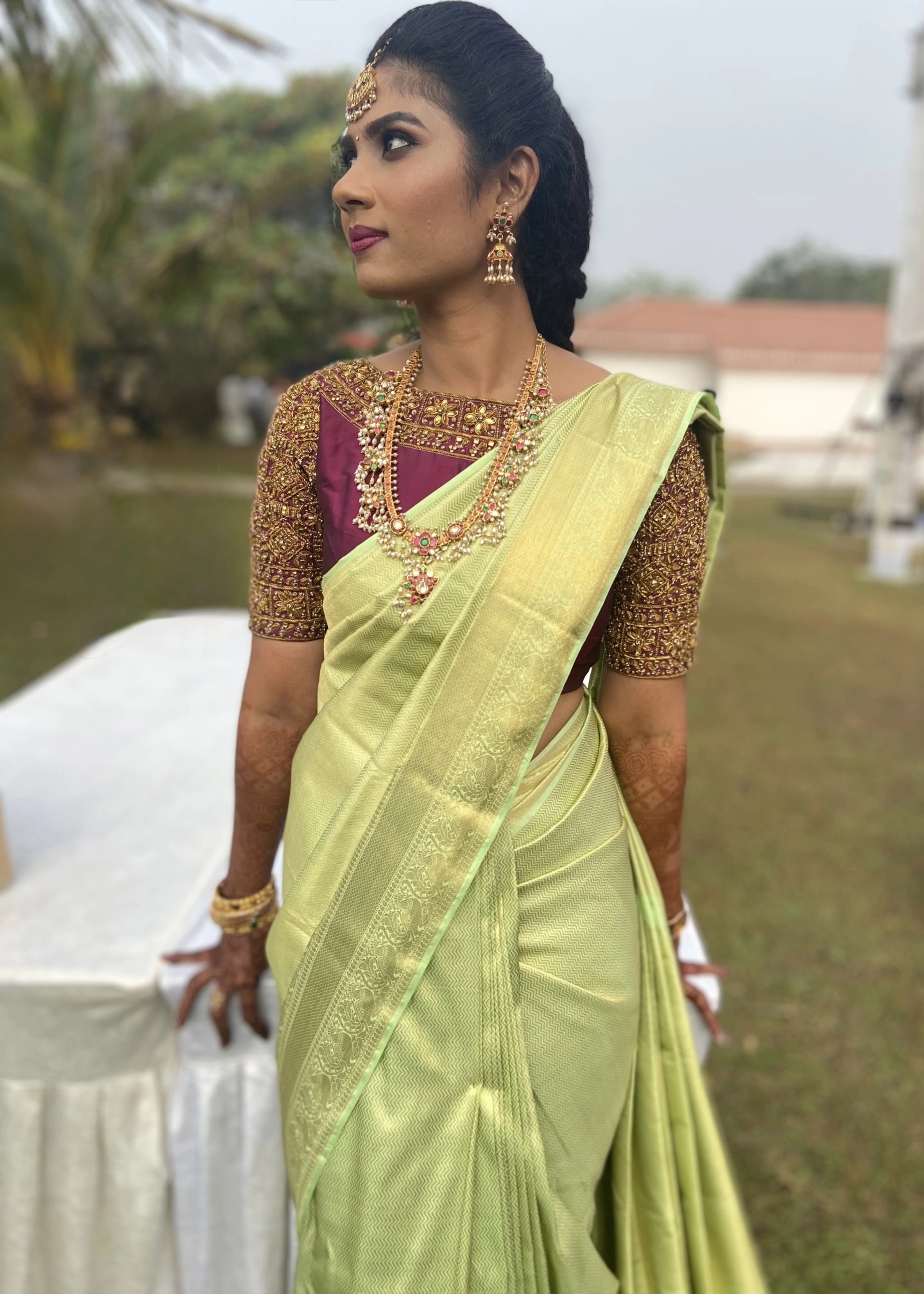Bridesmaid from Chennai looking away in a wine red silk blouse handcrafted intricately with zardozi and kemp stones designed by Archana Karthick.