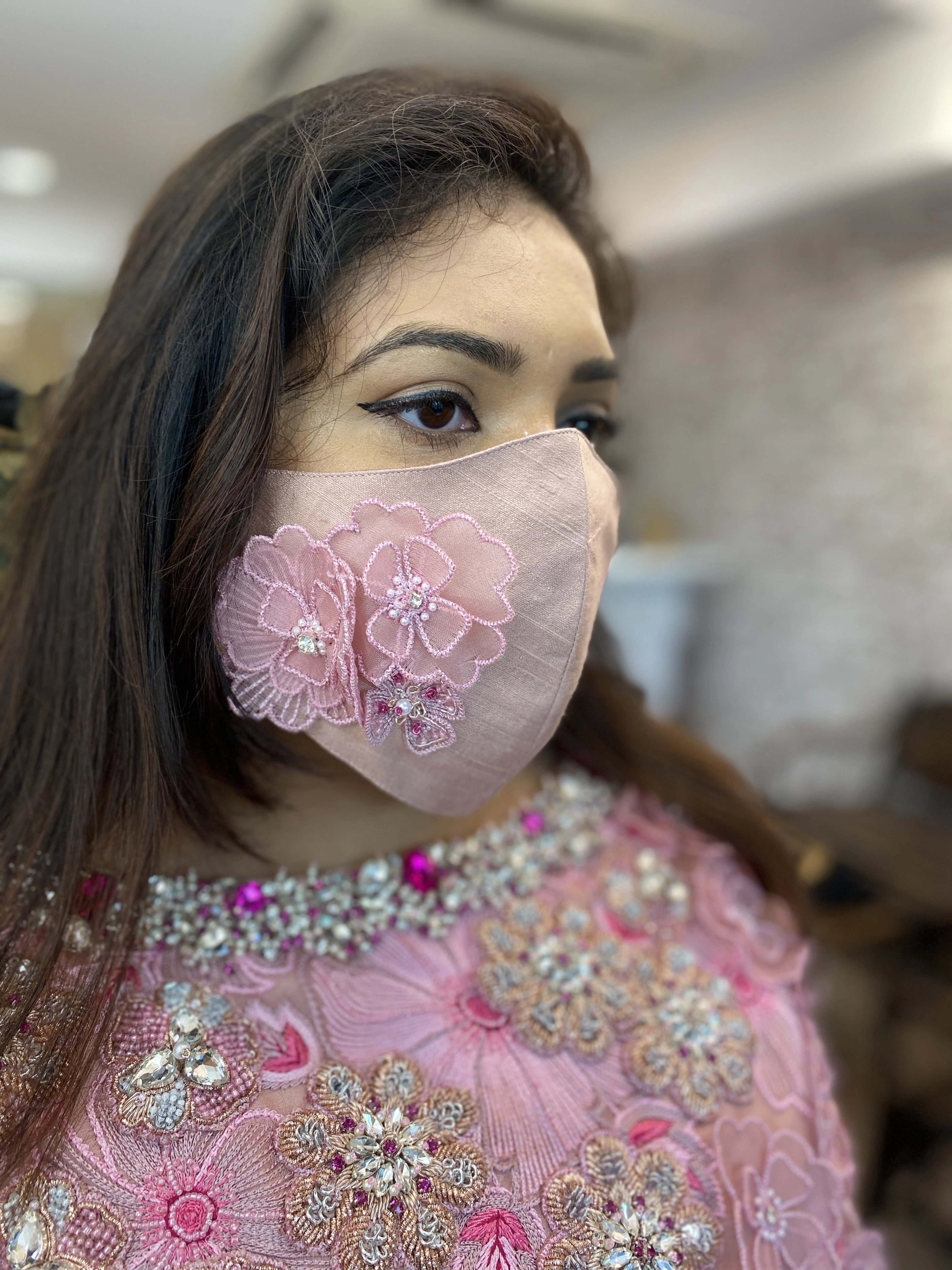 Bridesmaid from Chennai posing for side profile in a pink organza gown and mask handcrafted intricately with zardozi, stones, pearls and 3D floral appliques designed by Archana Karthick.