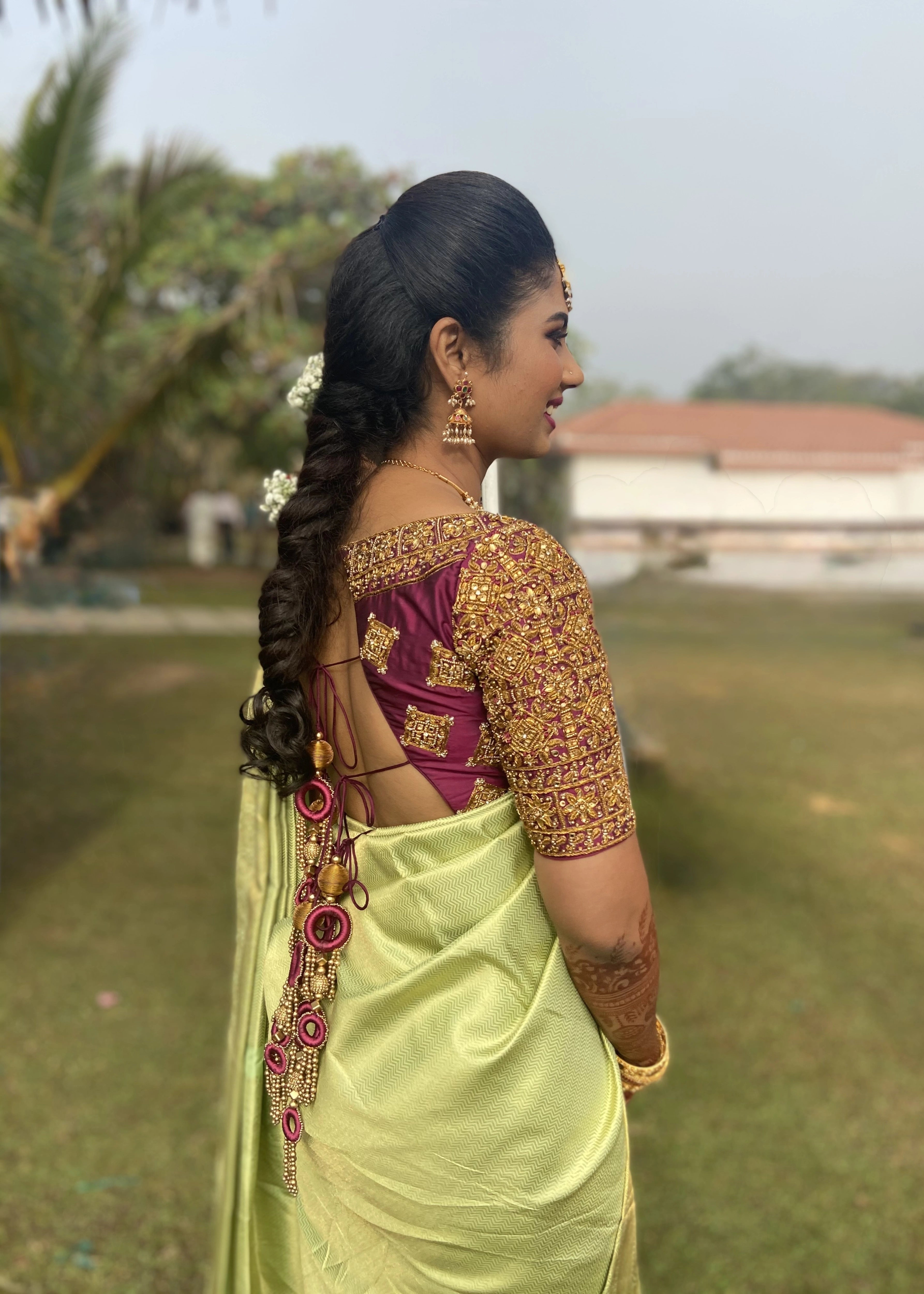 Bridesmaid from Chennai posing in a wine red silk blouse handcrafted intricately with zardozi and kemp stones designed by Archana Karthick.