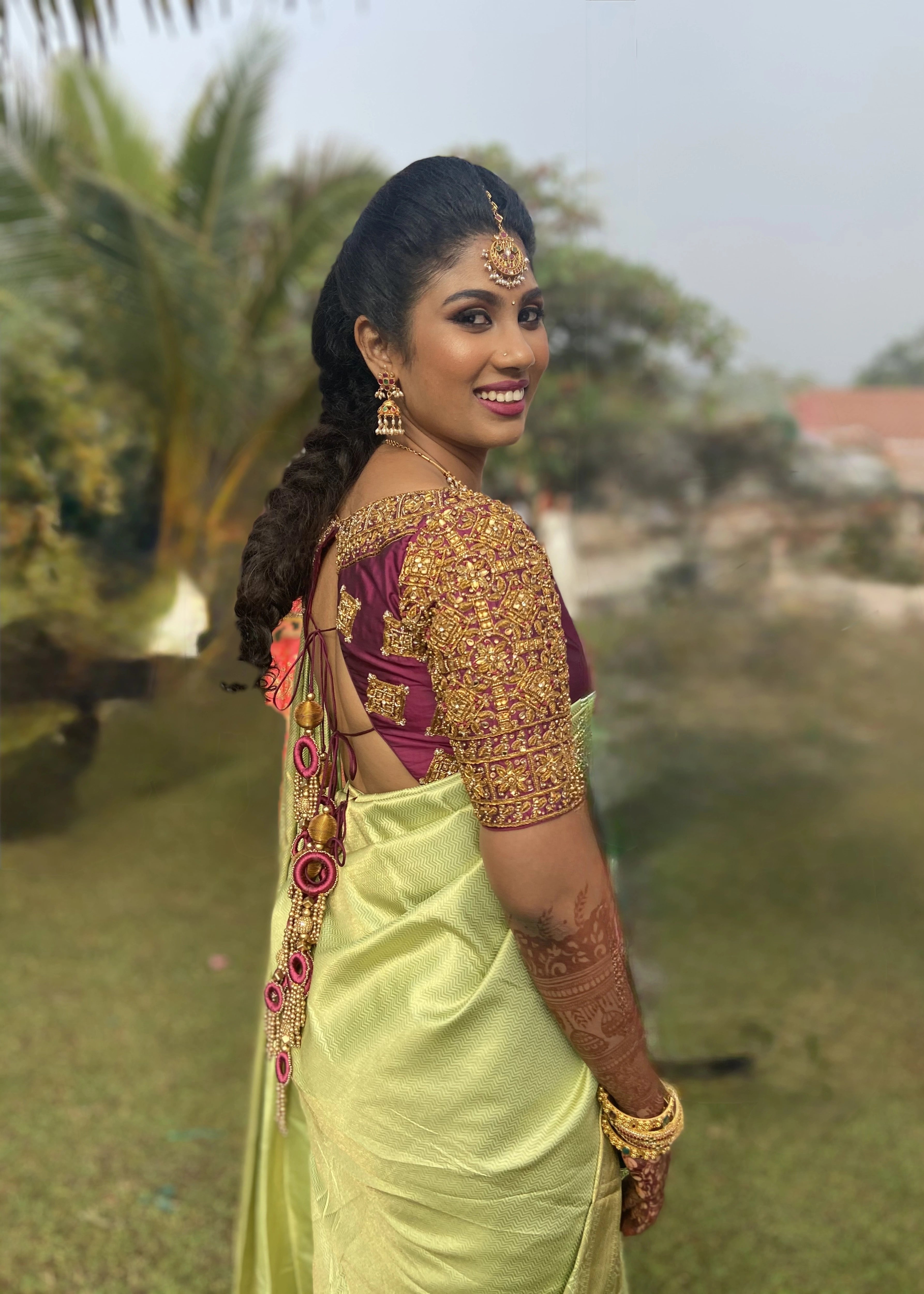 Bridesmaid from Chennai smiling in a wine red silk blouse handcrafted intricately with zardozi and kemp stones designed by Archana Karthick.