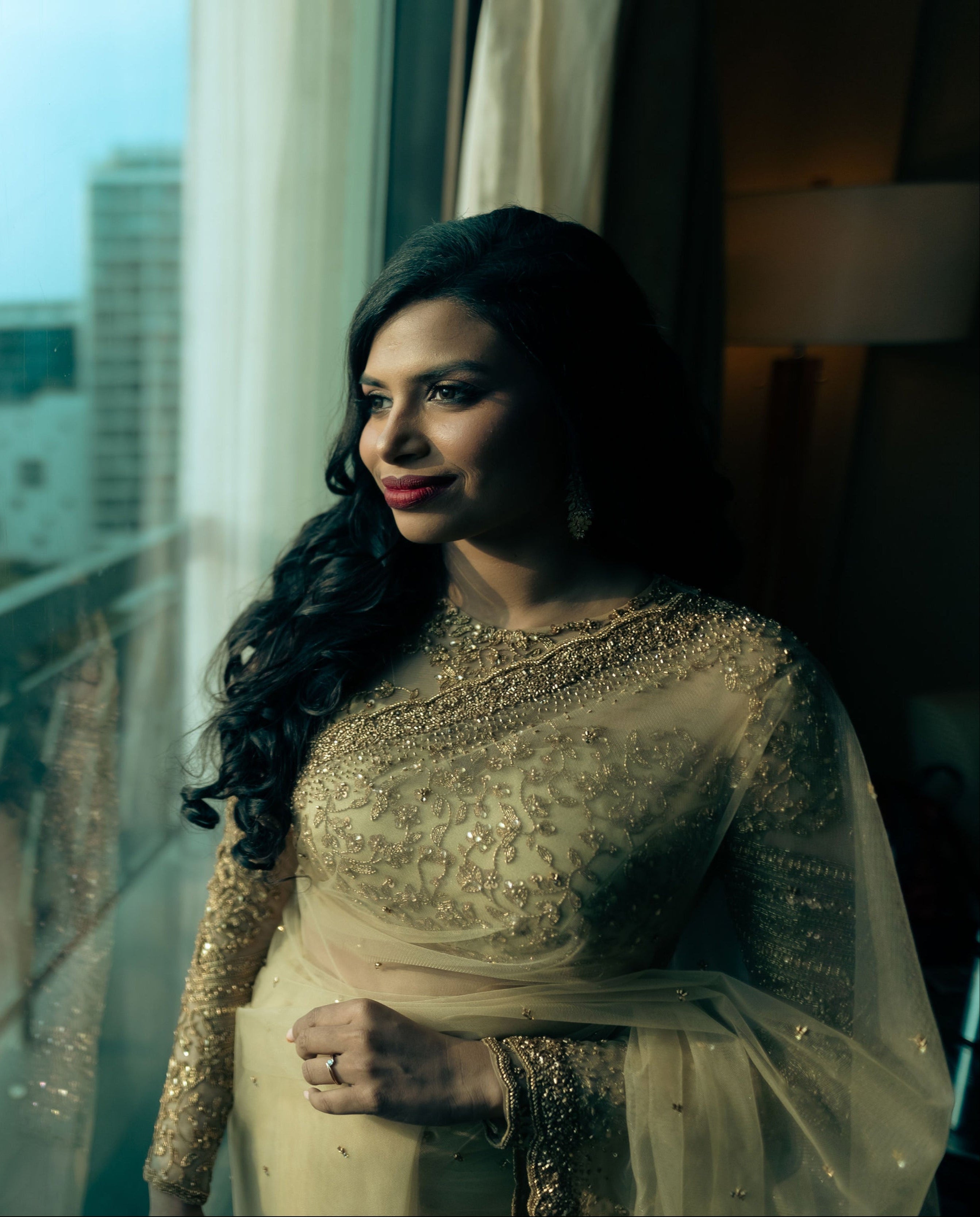 Christian Bride Steffi in handcrafted net saree in champagne gold designed by Archana Karthick. Posing looking out of the window for a full front profile of blouse and neckline.