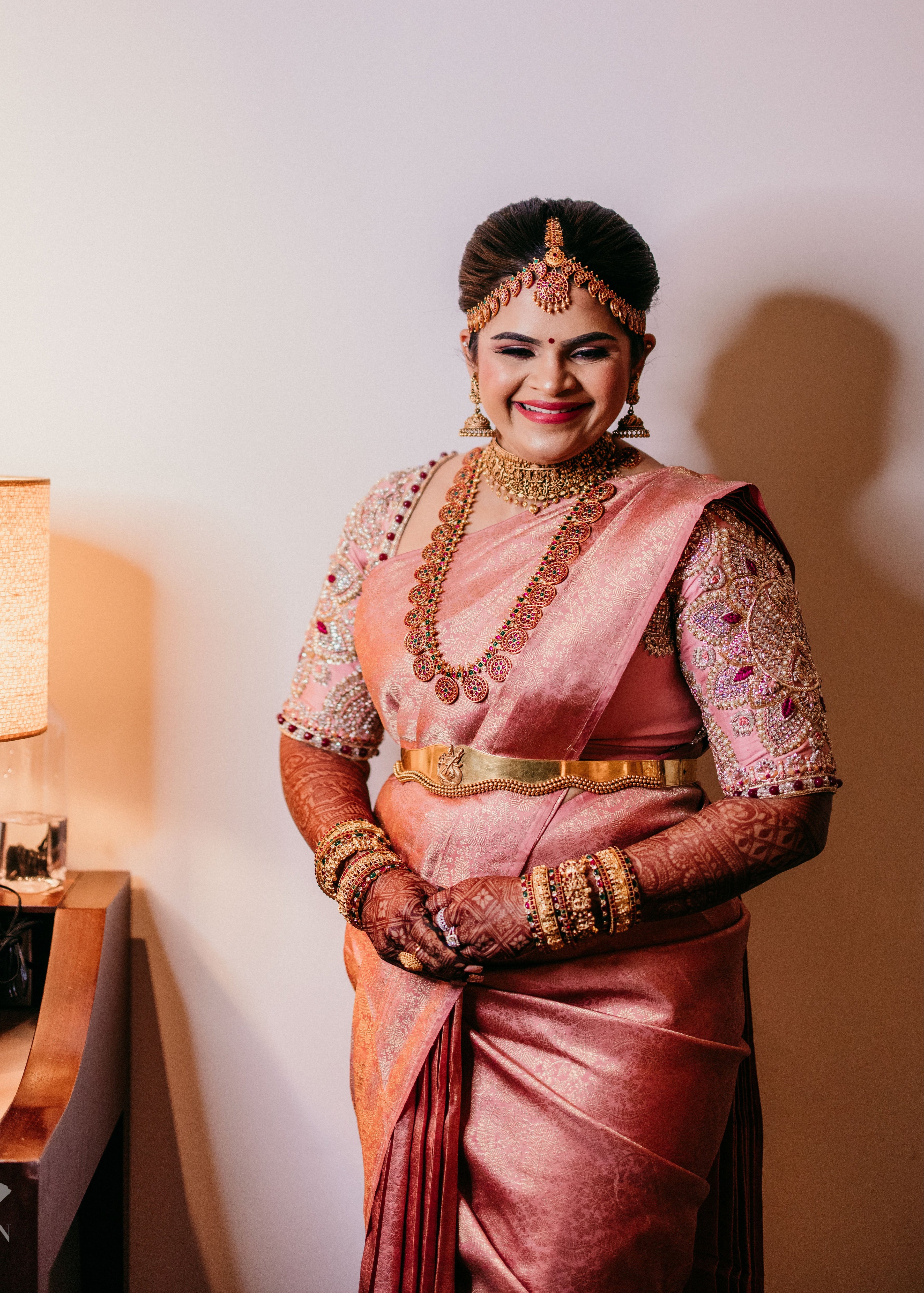 Comedian and actress Vidyu Raman smiling in a palanquin concept pink blouse handcrafted intricately with resham knot work, cut dana, crystal, pearls, swarovski stones and sequins designed by Archana Karthick.
