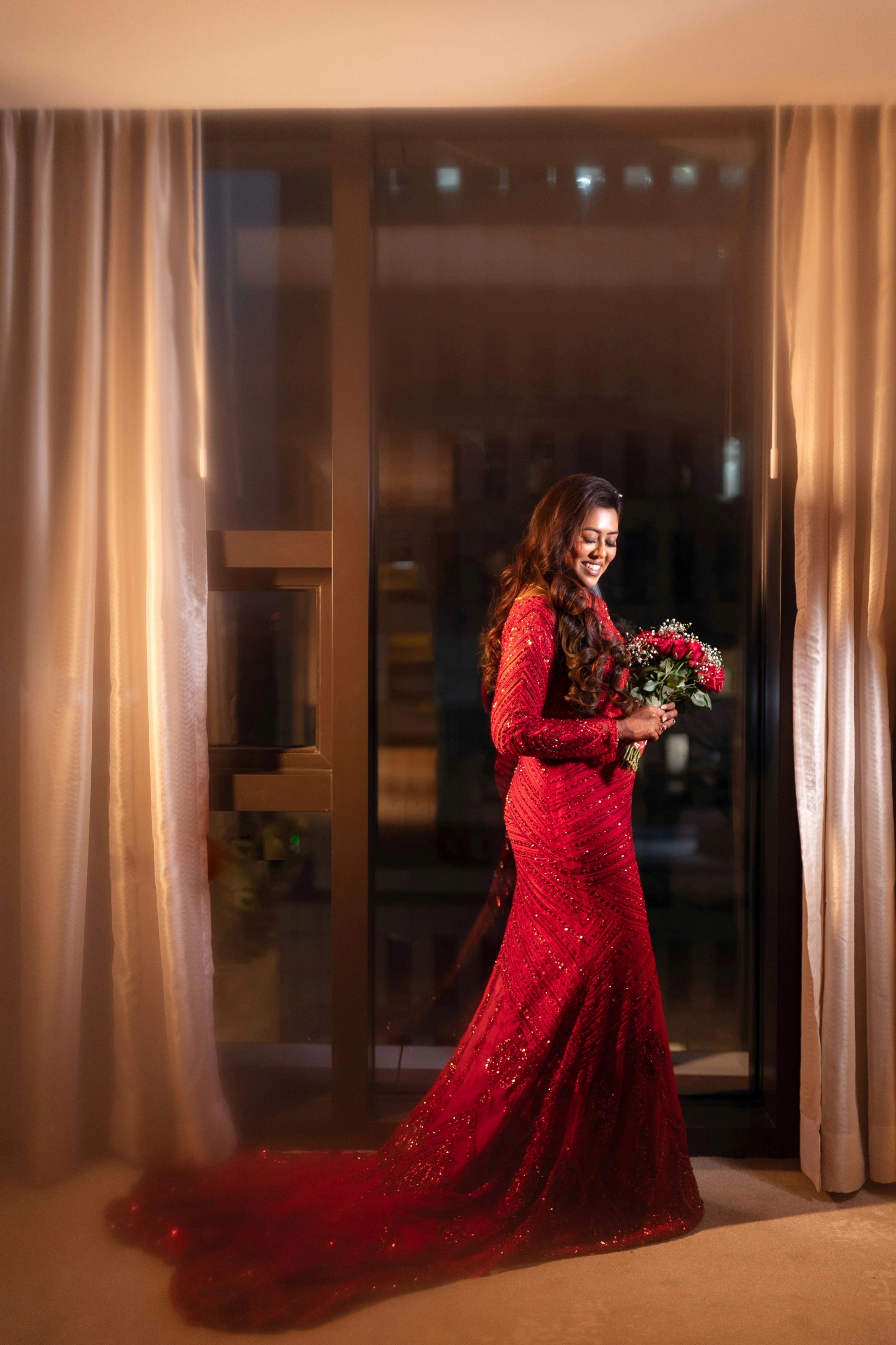 Dr Vishu Priya posing in a ruby red mermaid gown intricately handcrafted by team Archana Karthick.