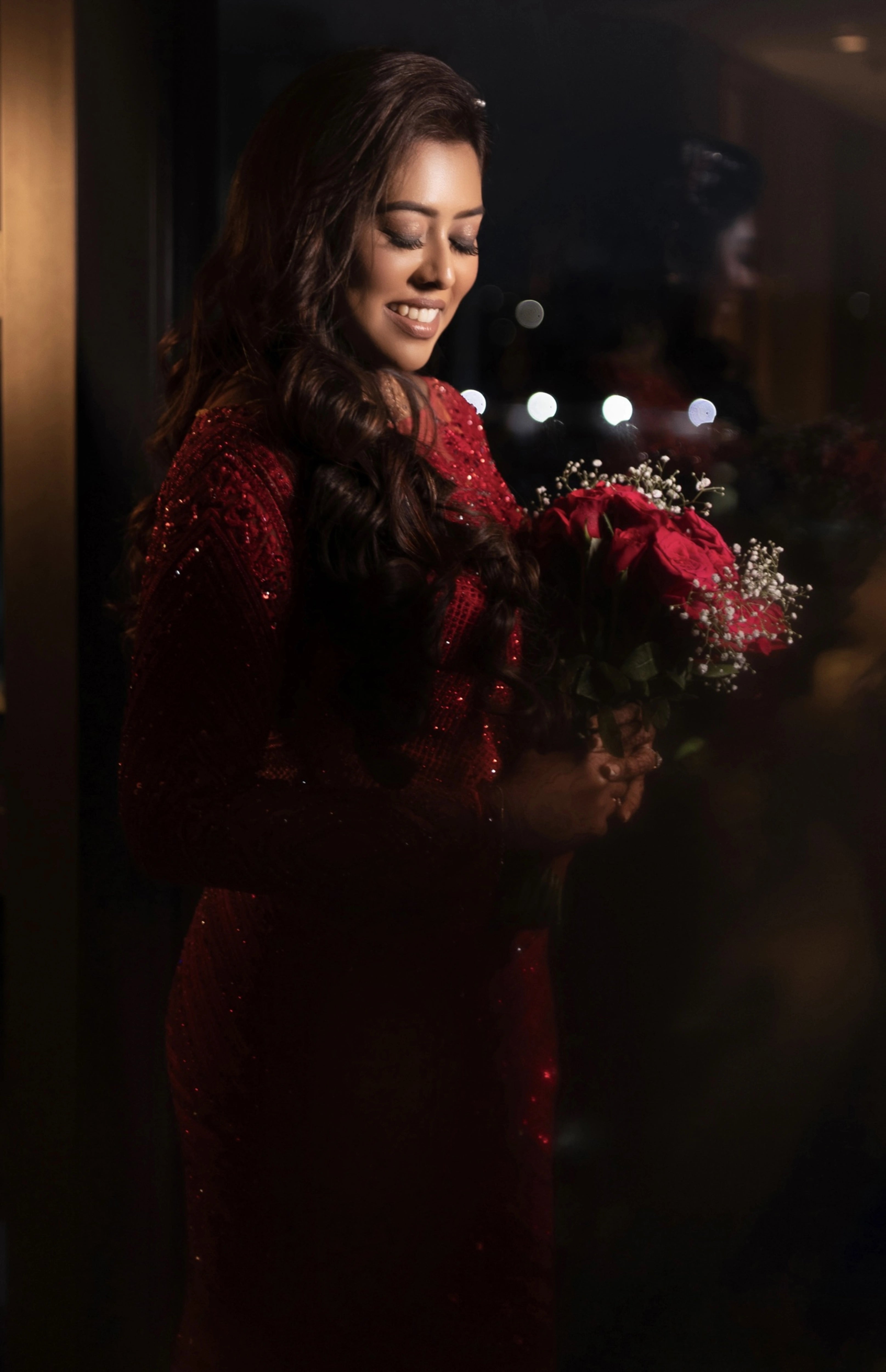 Dr Vishu Priya smiling in a ruby red mermaid gown intricately handcrafted by team Archana Karthick.