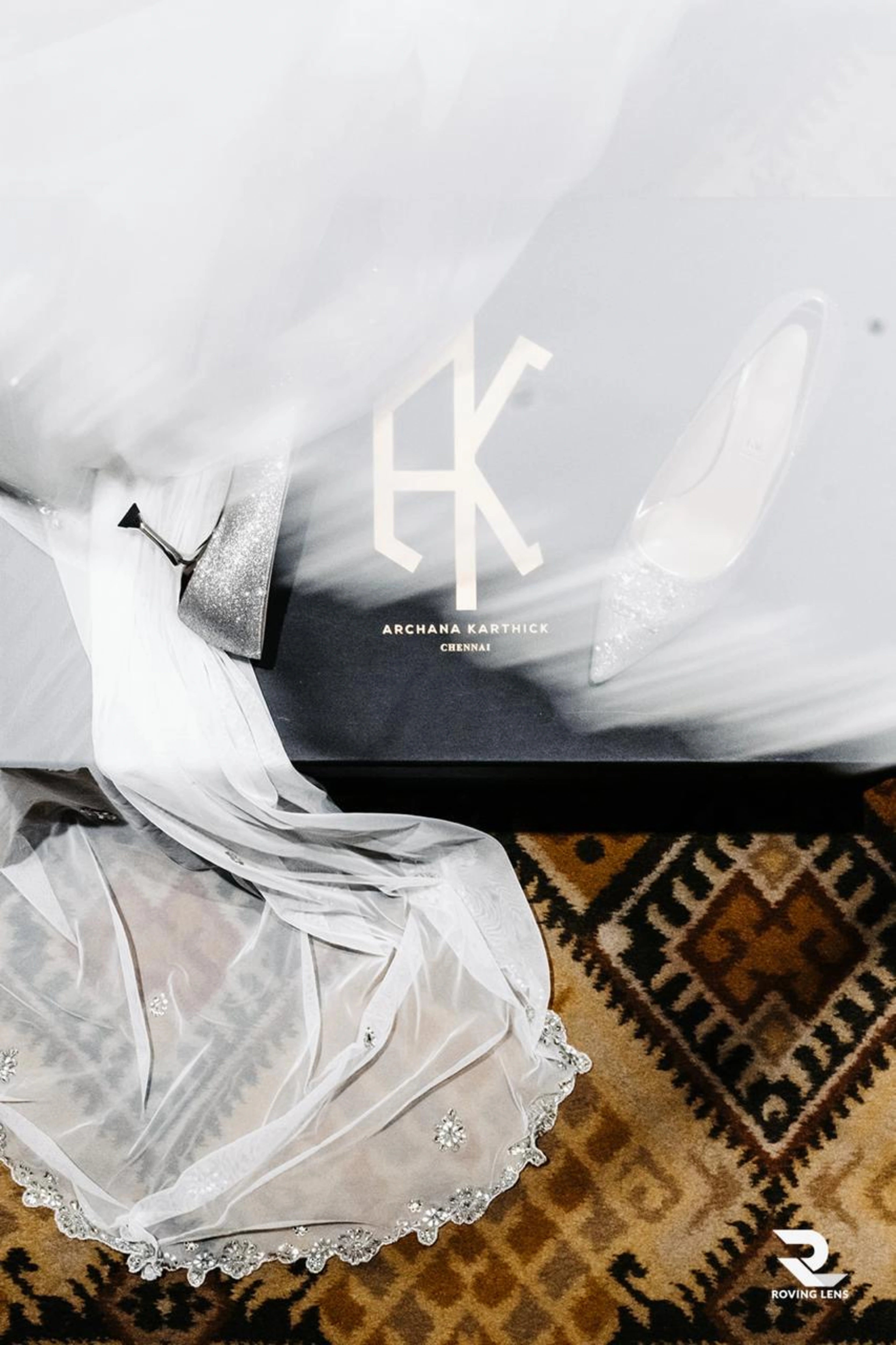 Elegant white dress with lace details on a textured surface, featuring Archana Karthick brand logo.