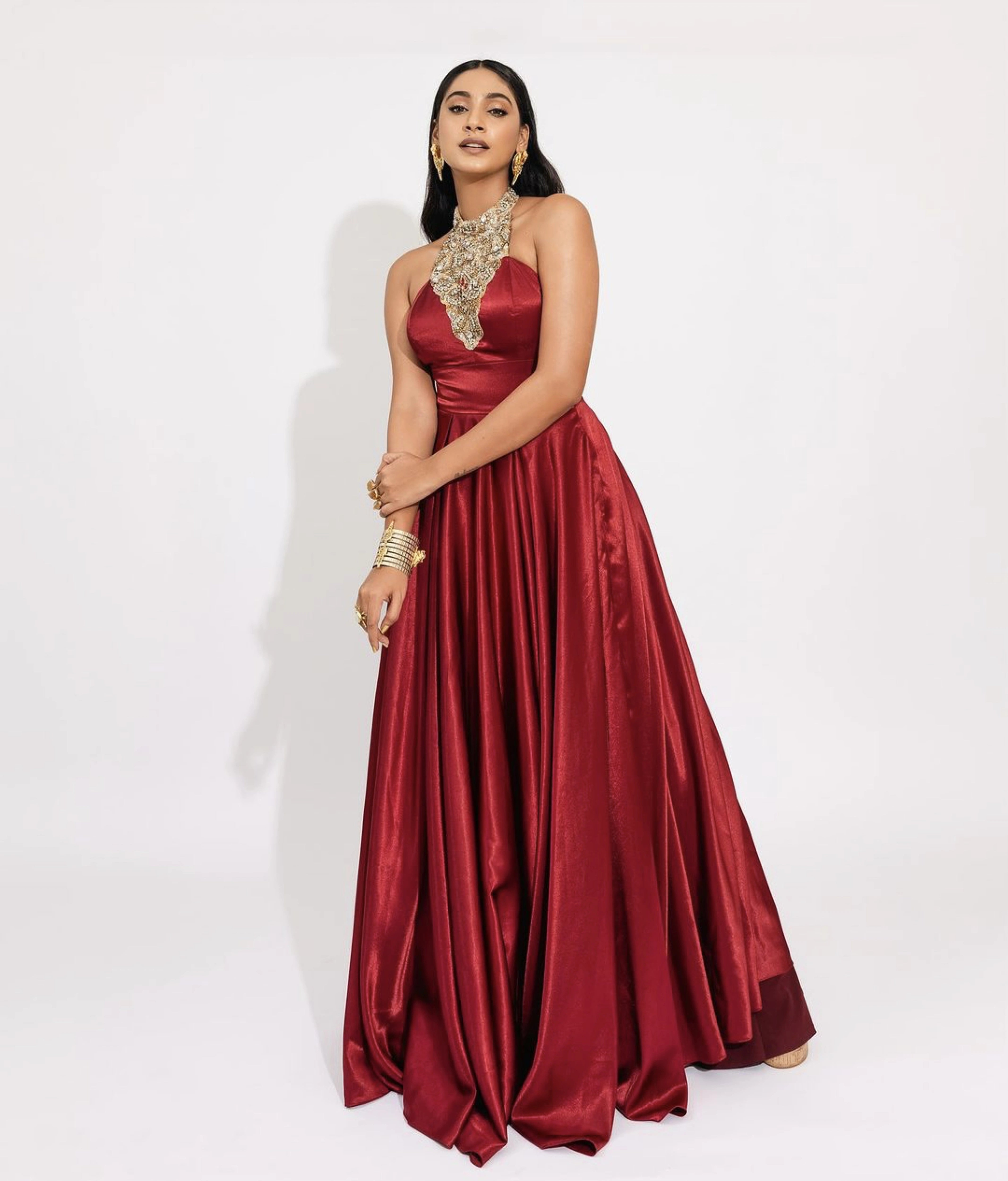 Former Miss India and Actress Anukreethy Vas posing in a red satin silk bejewled halterneck gown by team Archana Karthick.