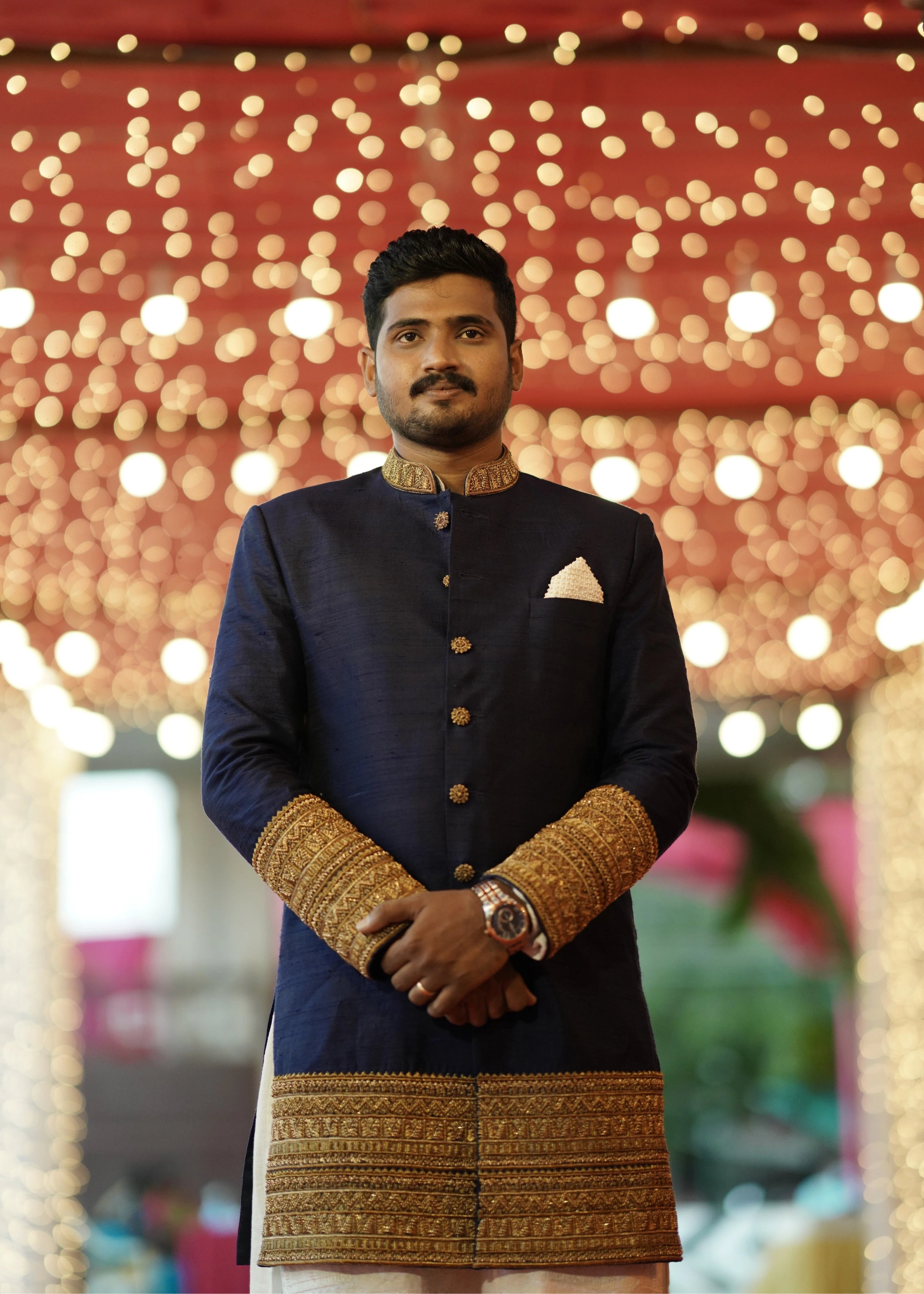 Groom Dinesh from Dindigul in a navy blue raw silk sherwani with embellished cuffs, collar and borders designed by Archana Karthick for his reception