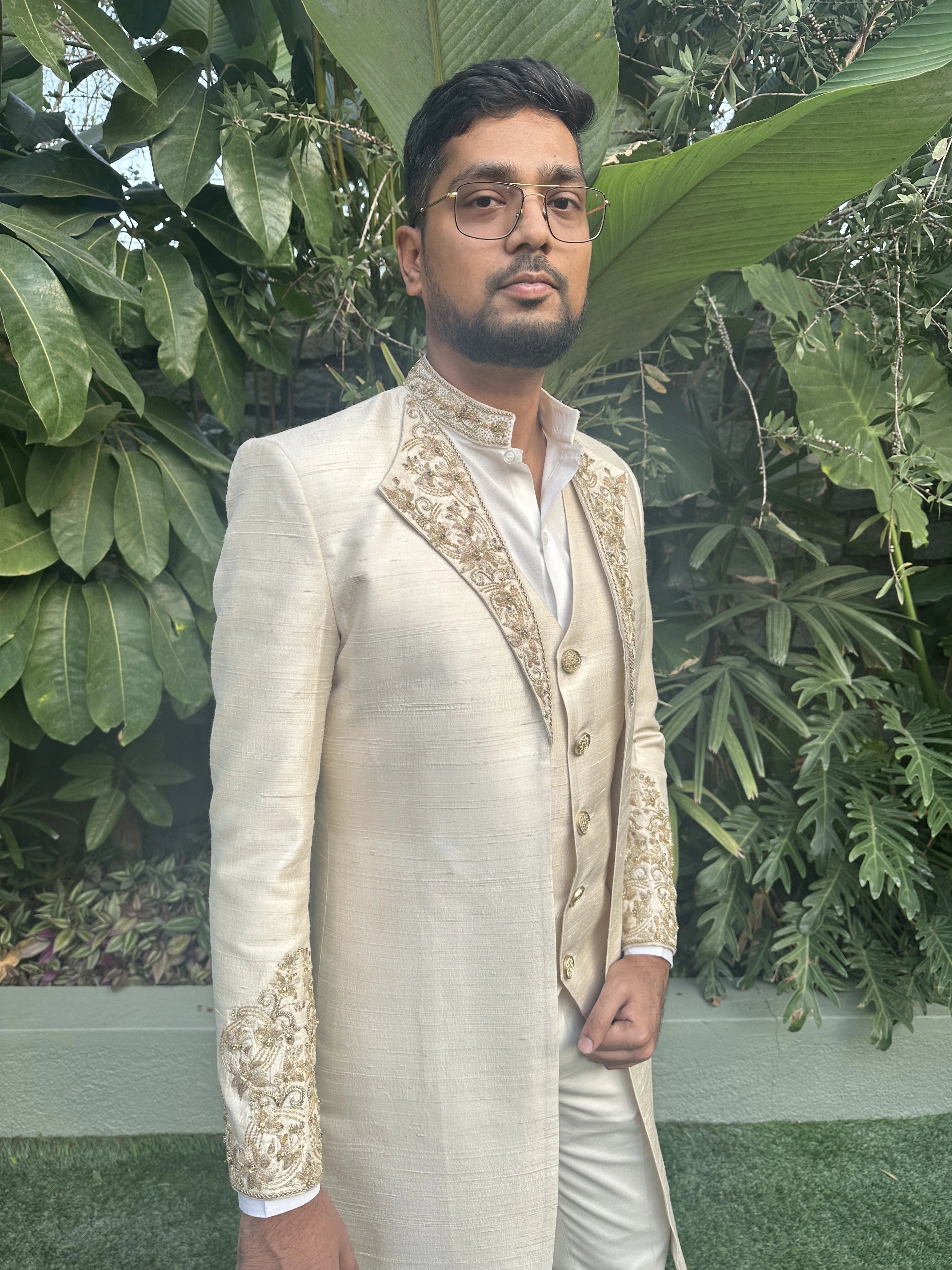 Groom Mahesh from bangalore posing for photo in an ivory raw silk sherwani handcrafted by team Archana Karthick.