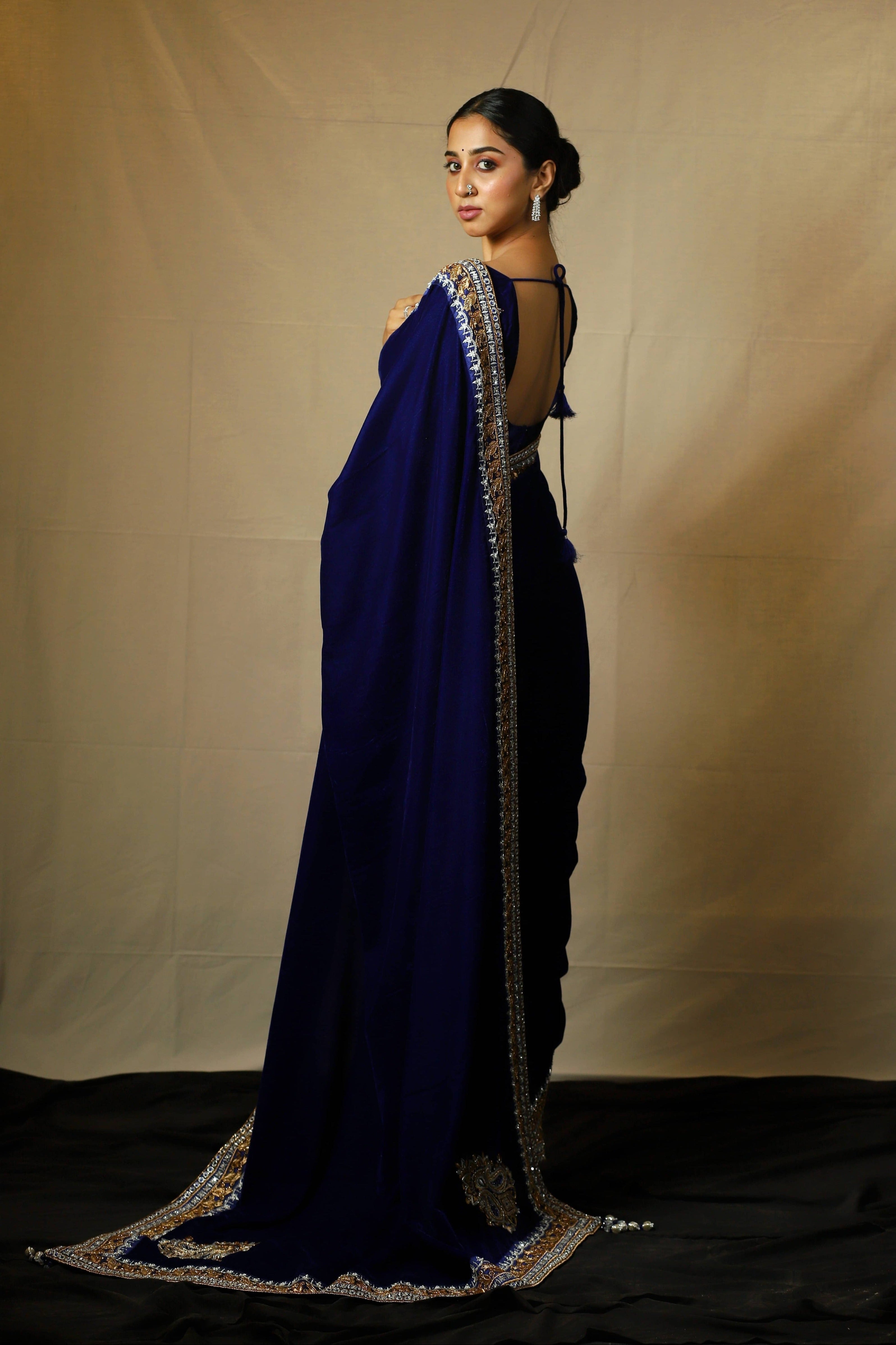 Influencer Deekshita Nikkam in a navy velvet saree and blouse set with zardozi detailings on border and sleeves. Side profile full