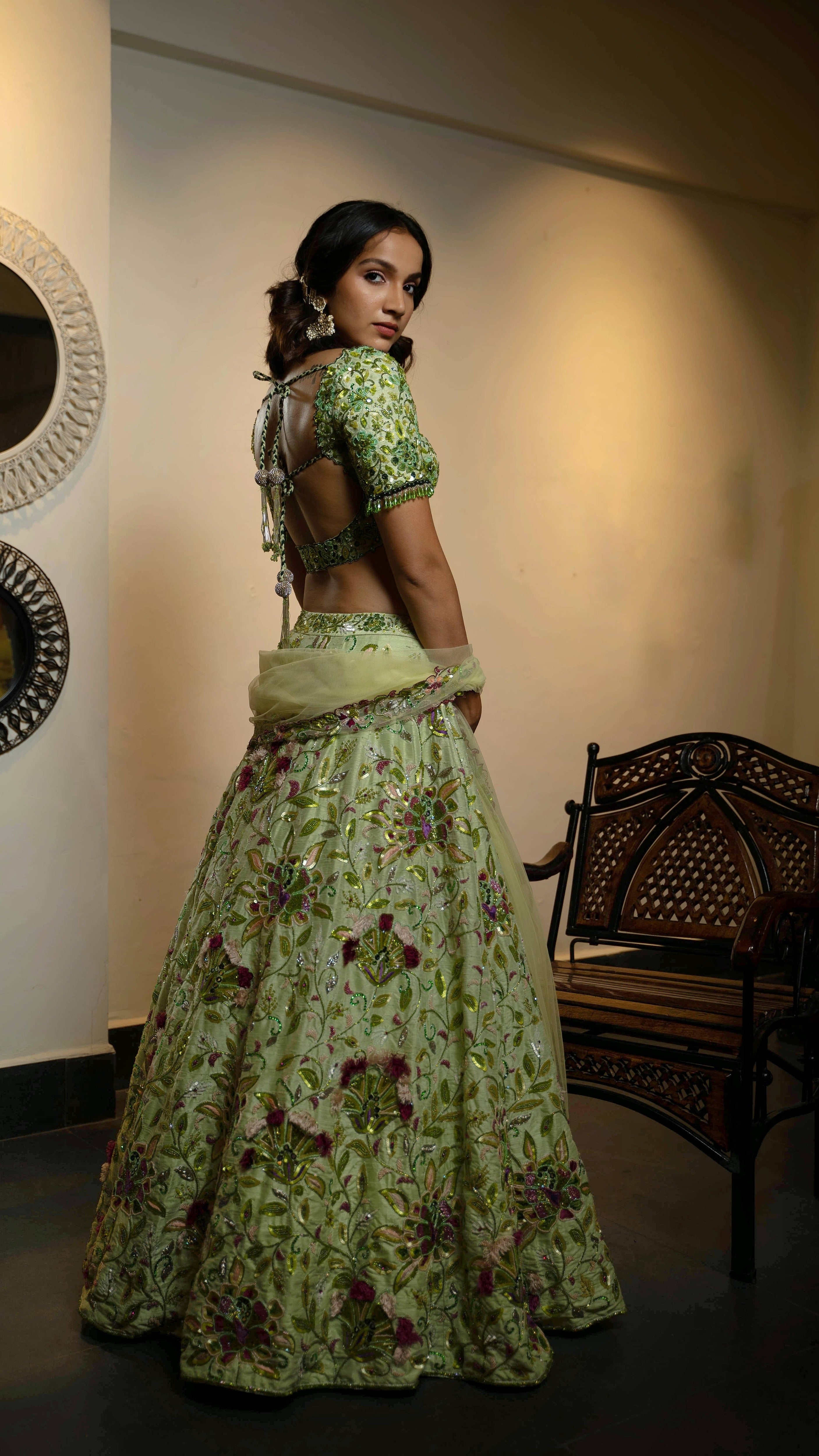 Influencer and actress Shweta Gai in a handcrafted green raw silk lehenga with floral motifs by Archana Karthick. Posing with dupatta around her hands and showing the blouse back design and tassels.