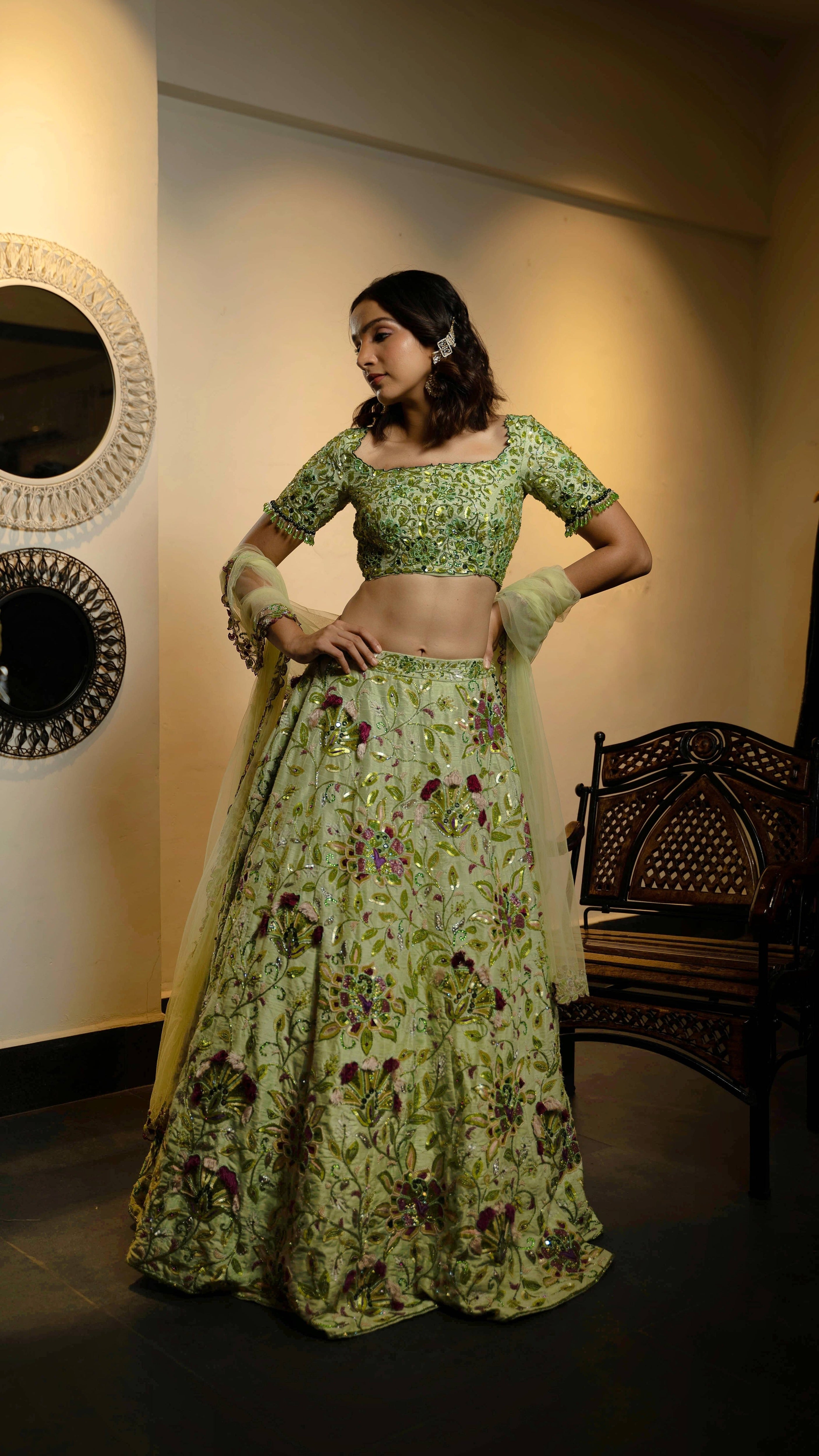 Influencer and actress Shweta Gai in a handcrafted green raw silk lehenga with floral motifs by Archana Karthick. Posing with hands on her hips looking to her right.