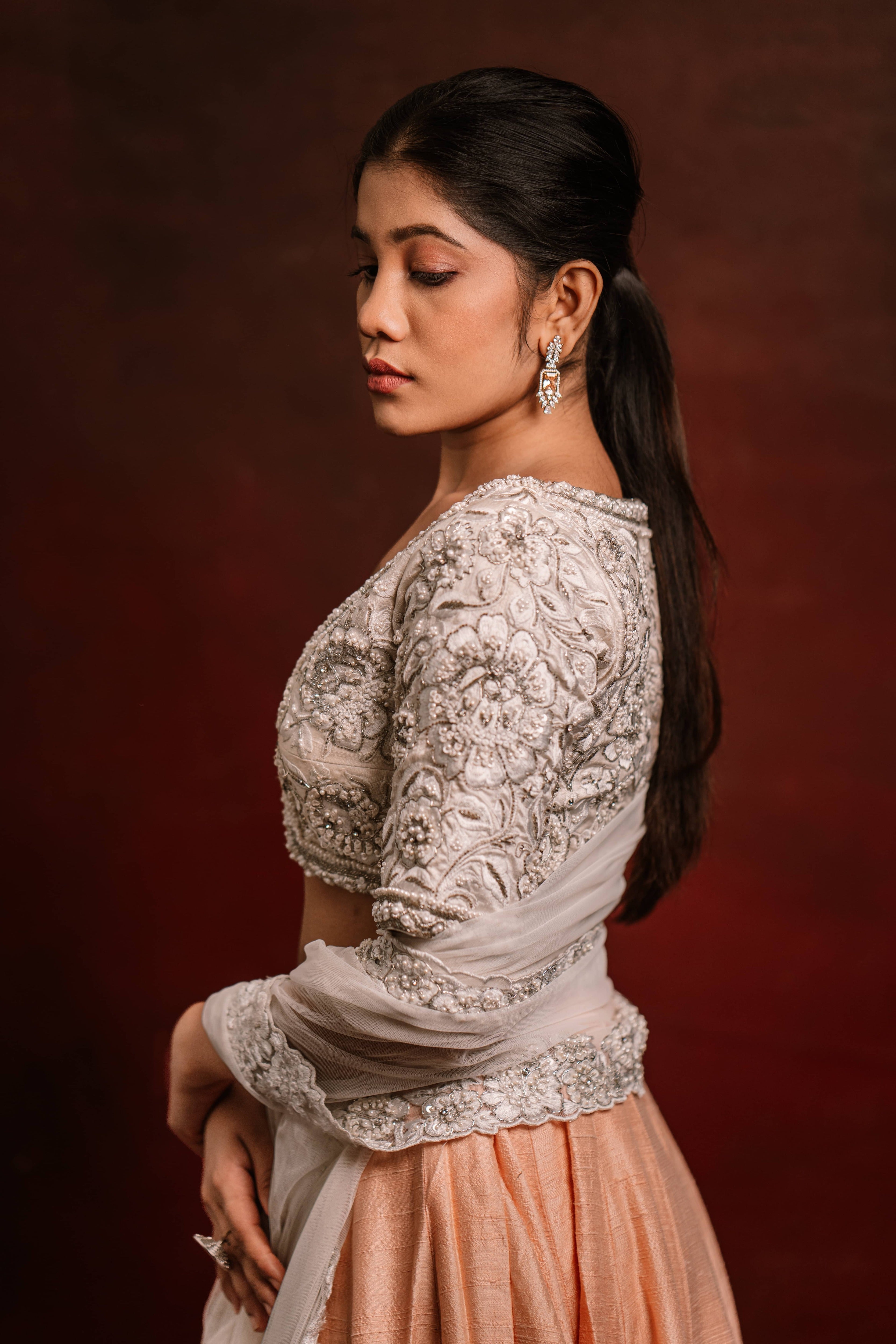 Jaina Parmar, known for recreating looks of actress Nayanthara is seen here posing in an ivory and peach raw silk lehenga with net dupatta. blouse and dupatta sleeve and border design captured