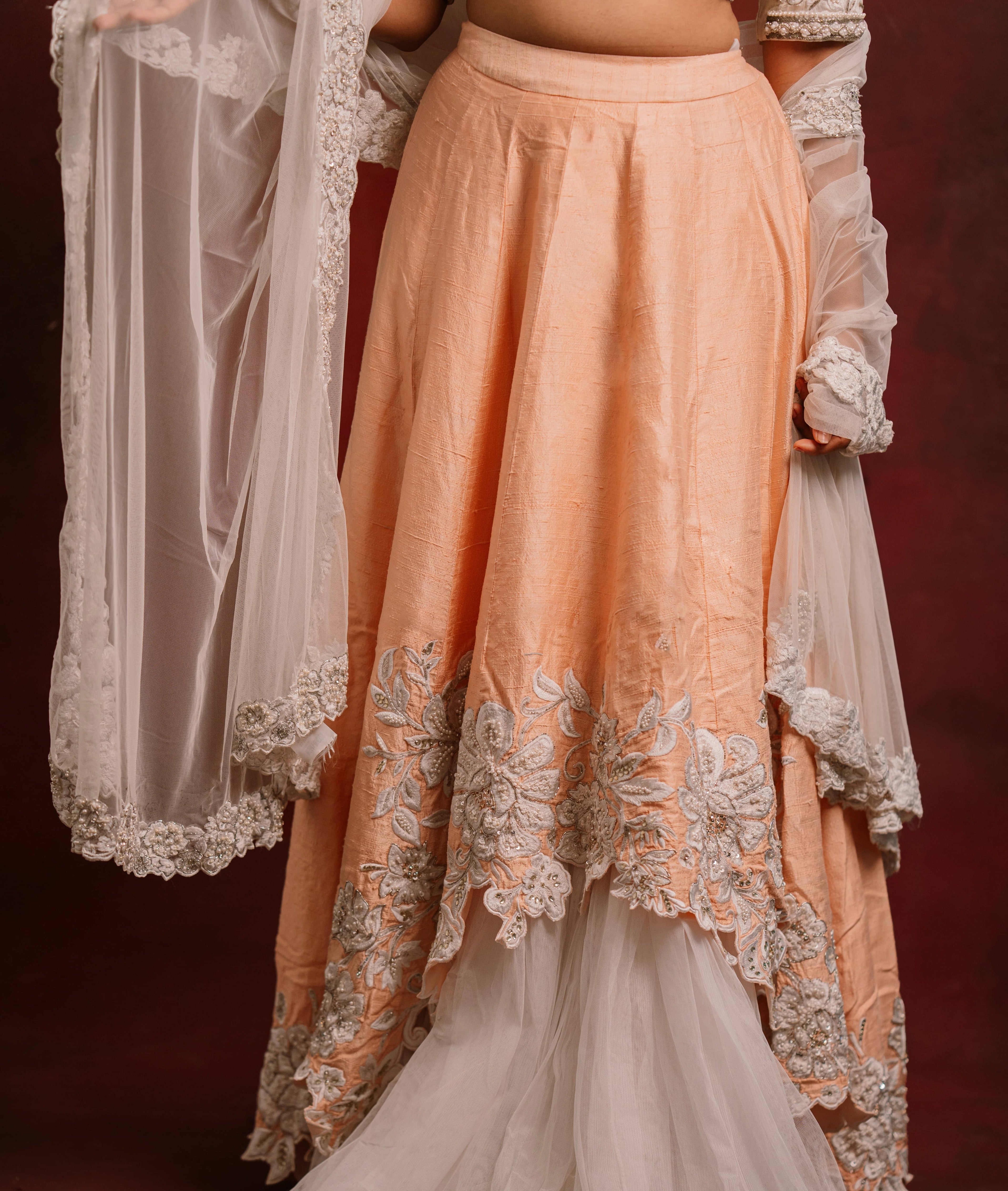 Jaina Parmar, known for recreating looks of actress Nayanthara is seen here posing in an ivory and peach raw silk lehenga with net dupatta. front skirt cut work and dupatta border design