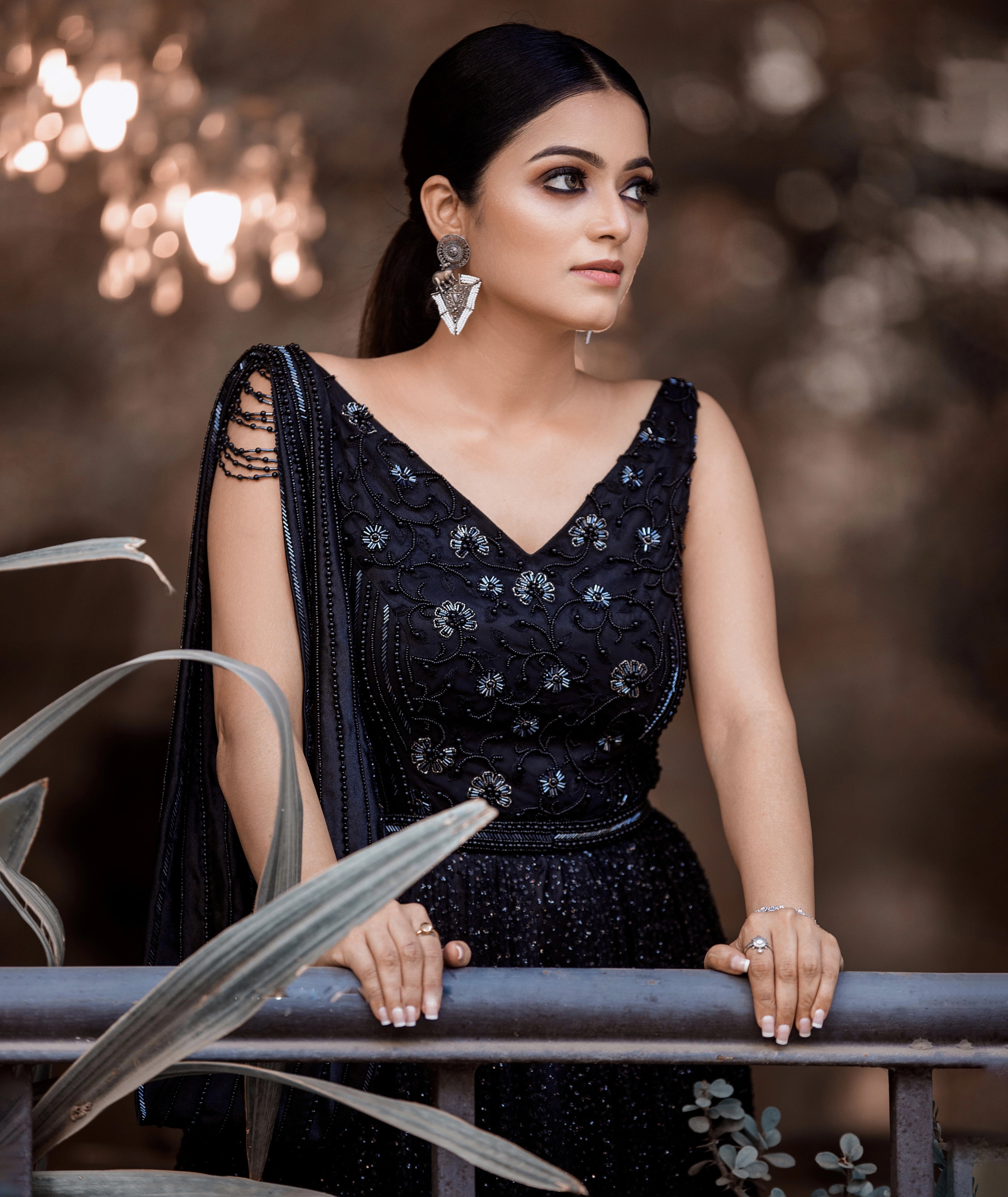 Janani Iyer looking left in a black net and satin gown with handcrafted drape, intricately designed with cutdana, sequins and beads by team Archana Karthick.