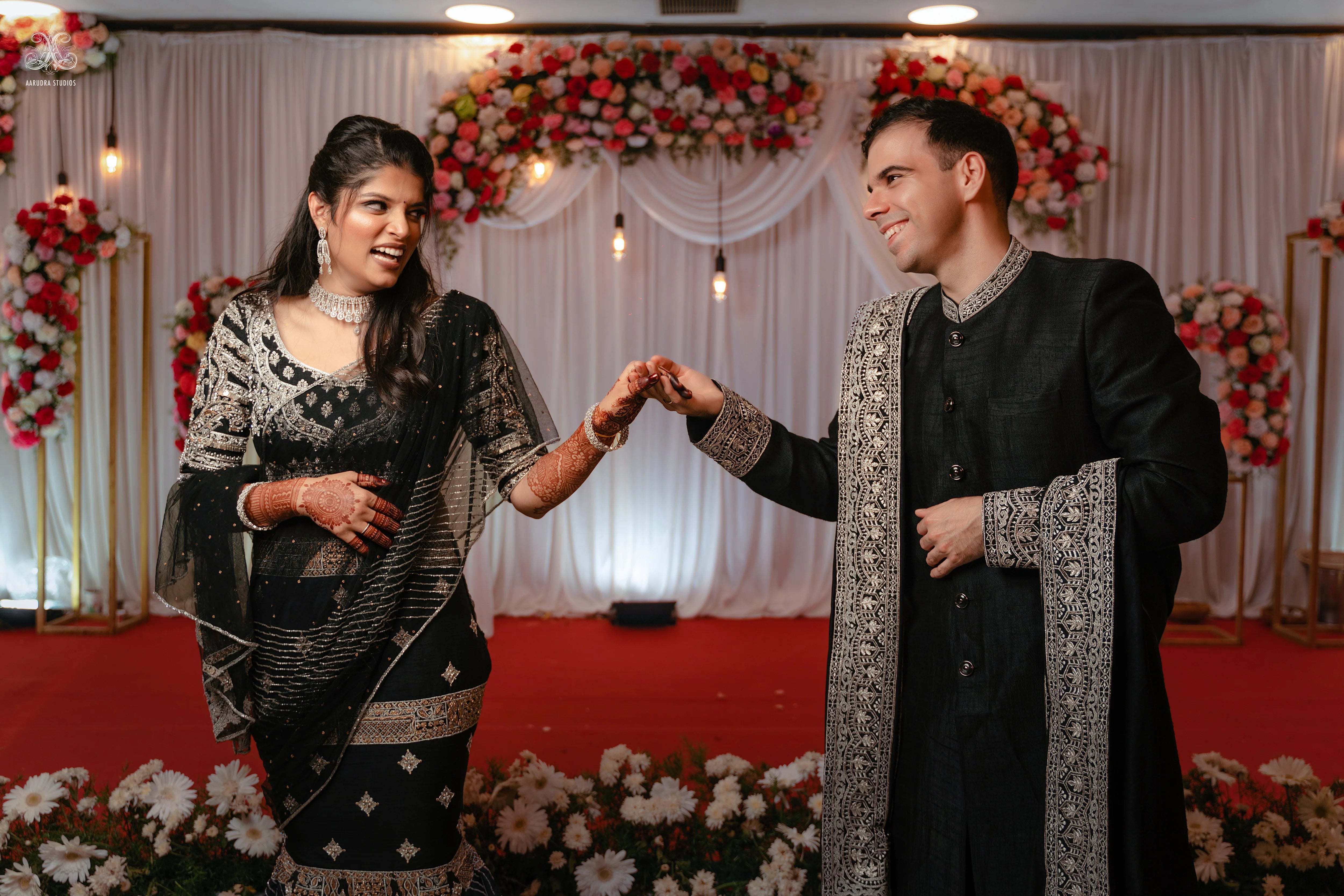 Kamakshi & Alex from Yokosuka, Japan, laughing in a black raw silk lehenga and sherwani handcrafted by team Archana Karthick.