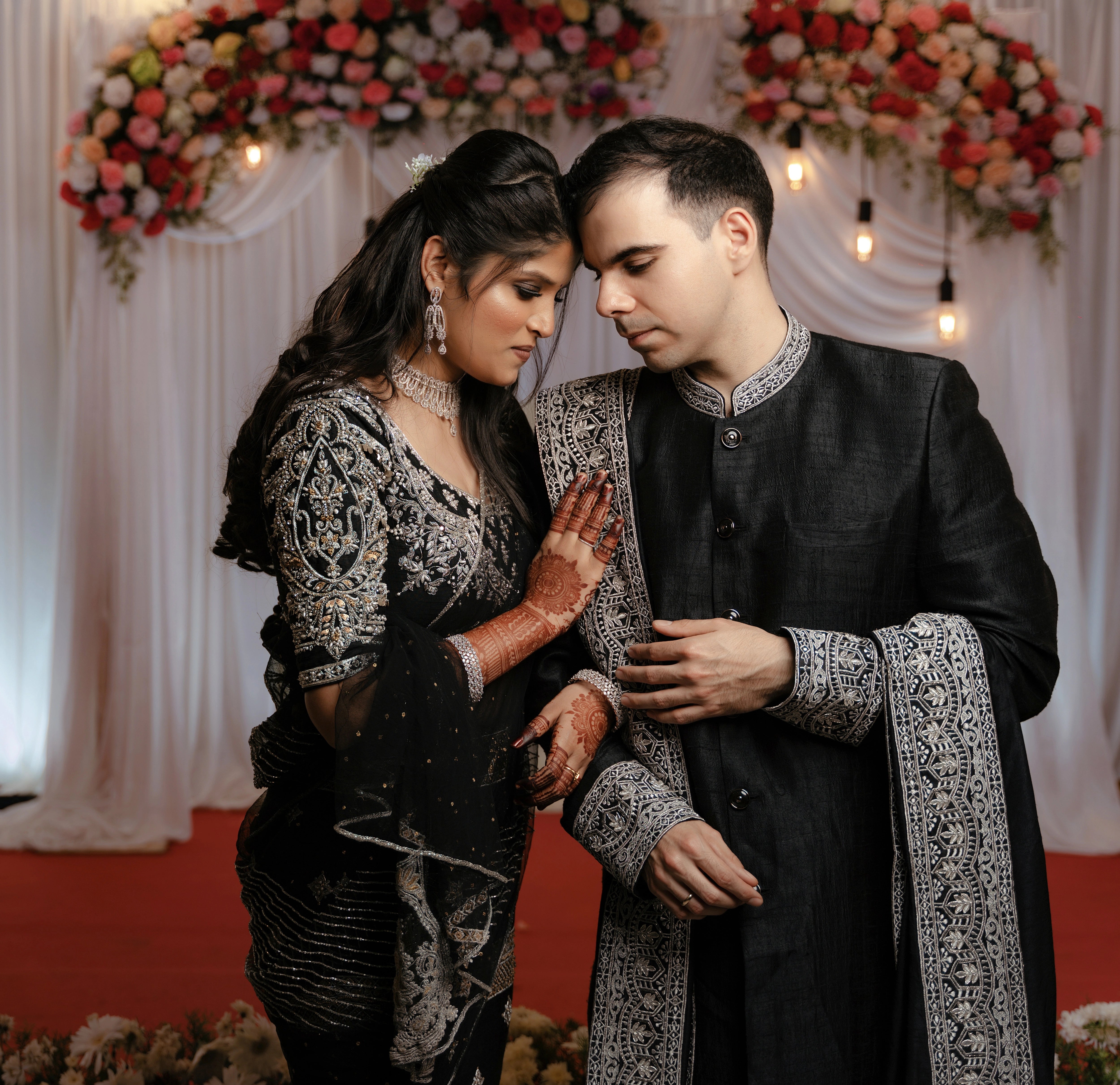 Kamakshi & Alex from Yokosuka, Japan, posing for photo in a black raw silk lehenga and sherwani handcrafted by team Archana Karthick.