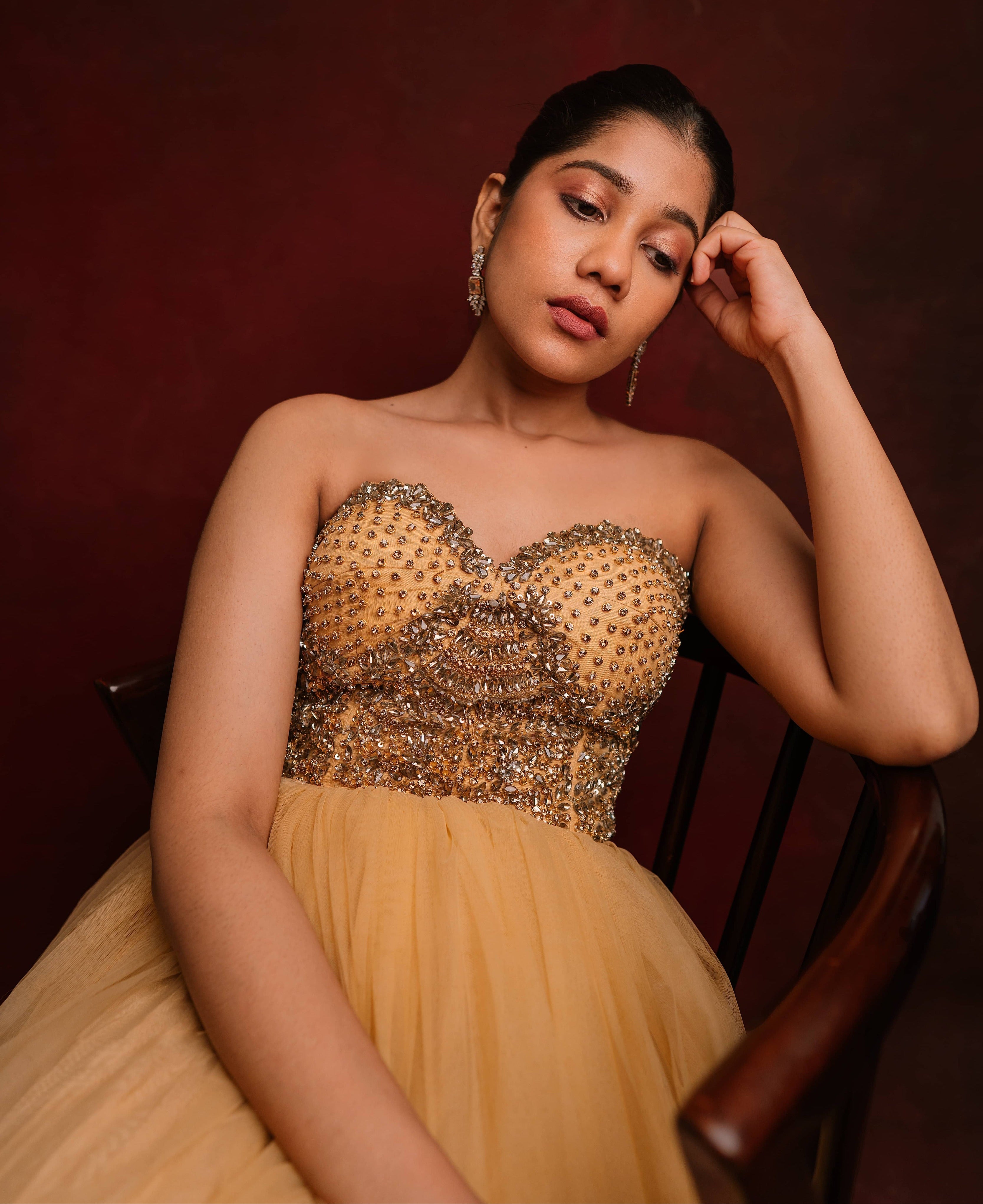 Looking down in a gold corset dress intricately handcrafted with stones and sequins designed by team Archana Karthick.