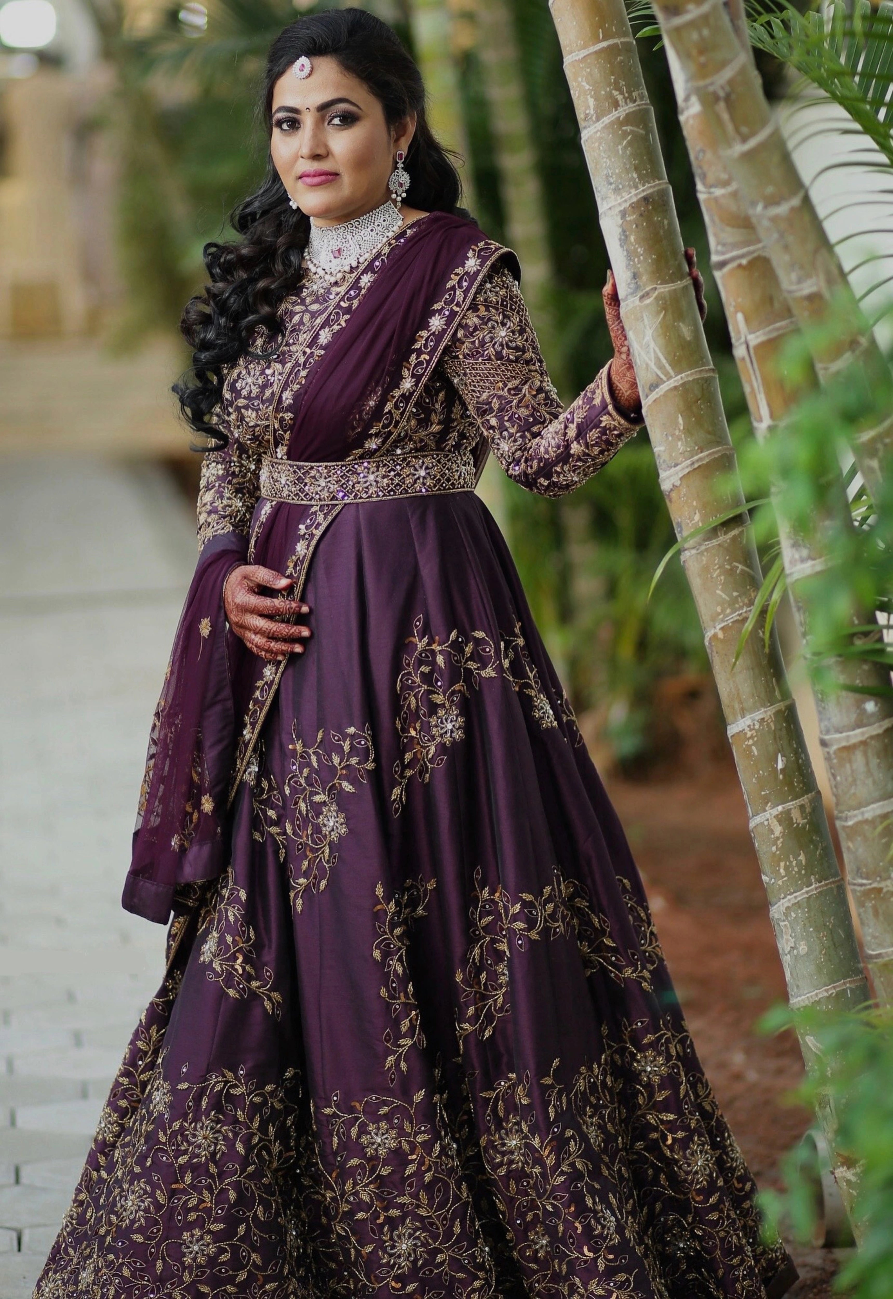 Bride Deepika in an eggplant colored raw silk draped gown with belt intricately embellished with cutdana, sequins, stones and beads by team Archana Karthick.