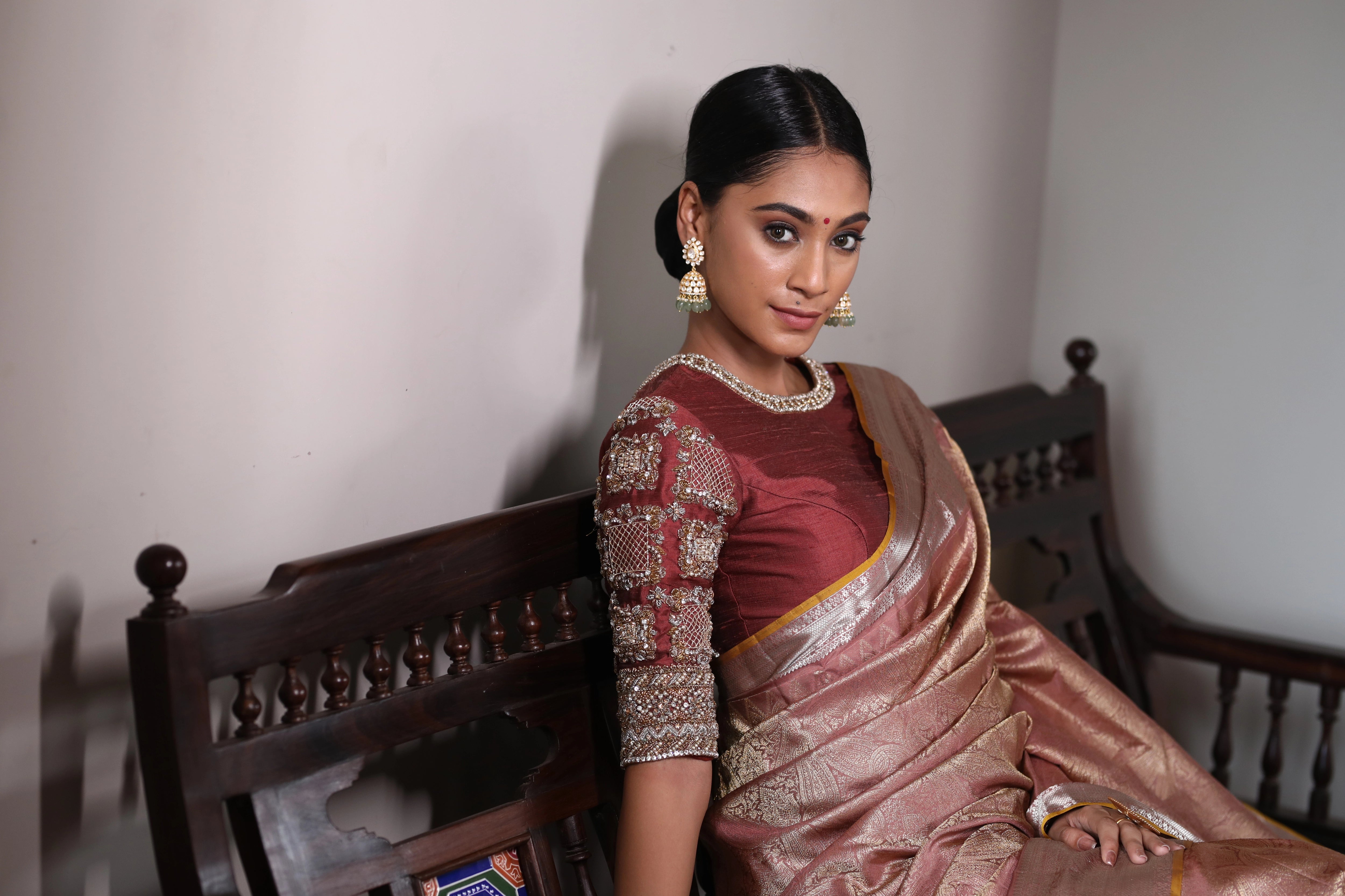 Miss India and Actress Anukreethy Vas posing seated in a rose gold raw silk blouse, intricately handcrafted with pearls, zardozi, stones and zari by team Archana Karthick.