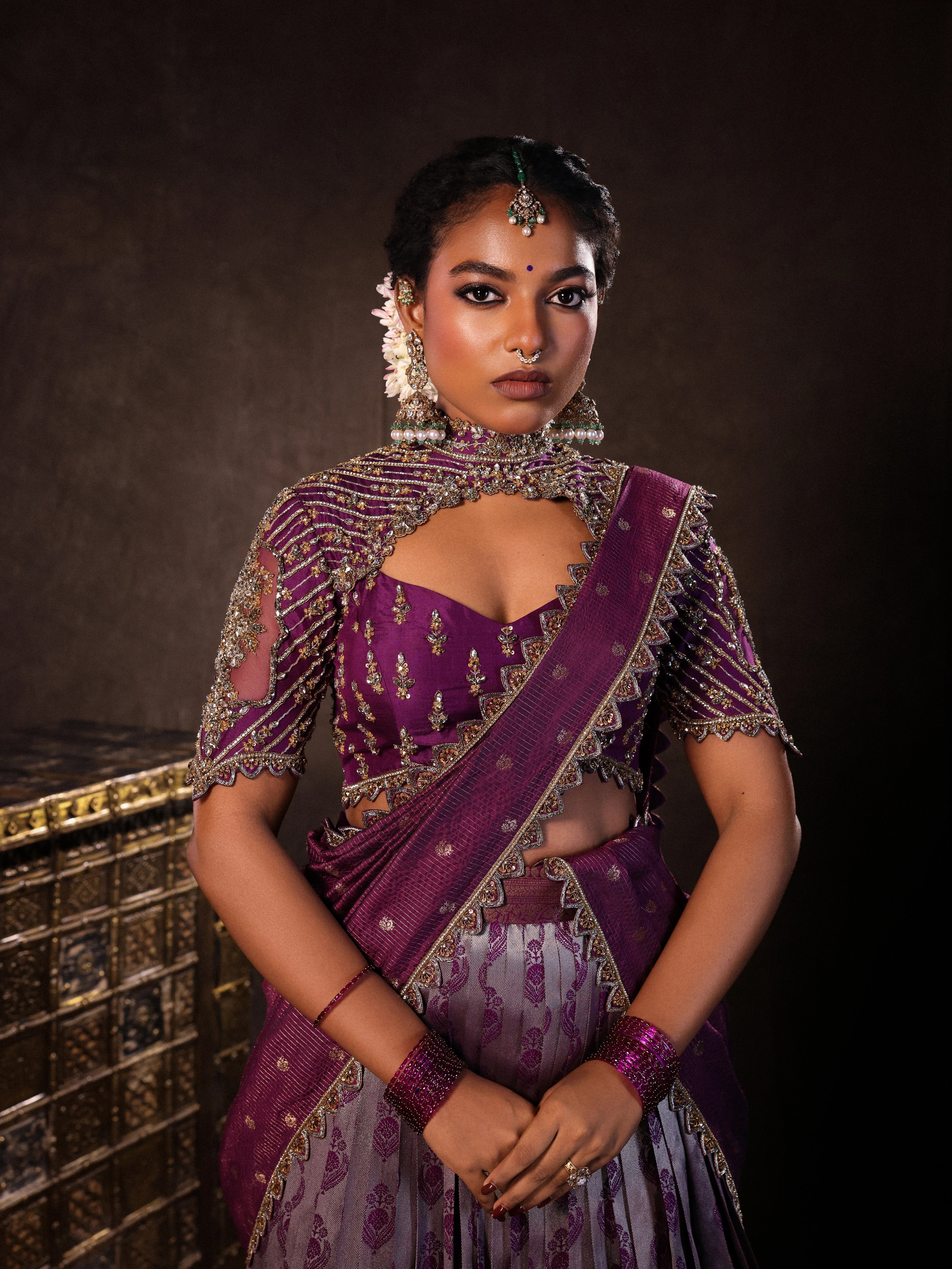 Model Ashika Crystal during photoshoot in a silk half saree set in purple, handcrafted with zardozi, sequins and rhinestones. Team Archana Karthick completed the style with purple glass bangles, a ring, jhumkas, nose ring and a maang tikka.
