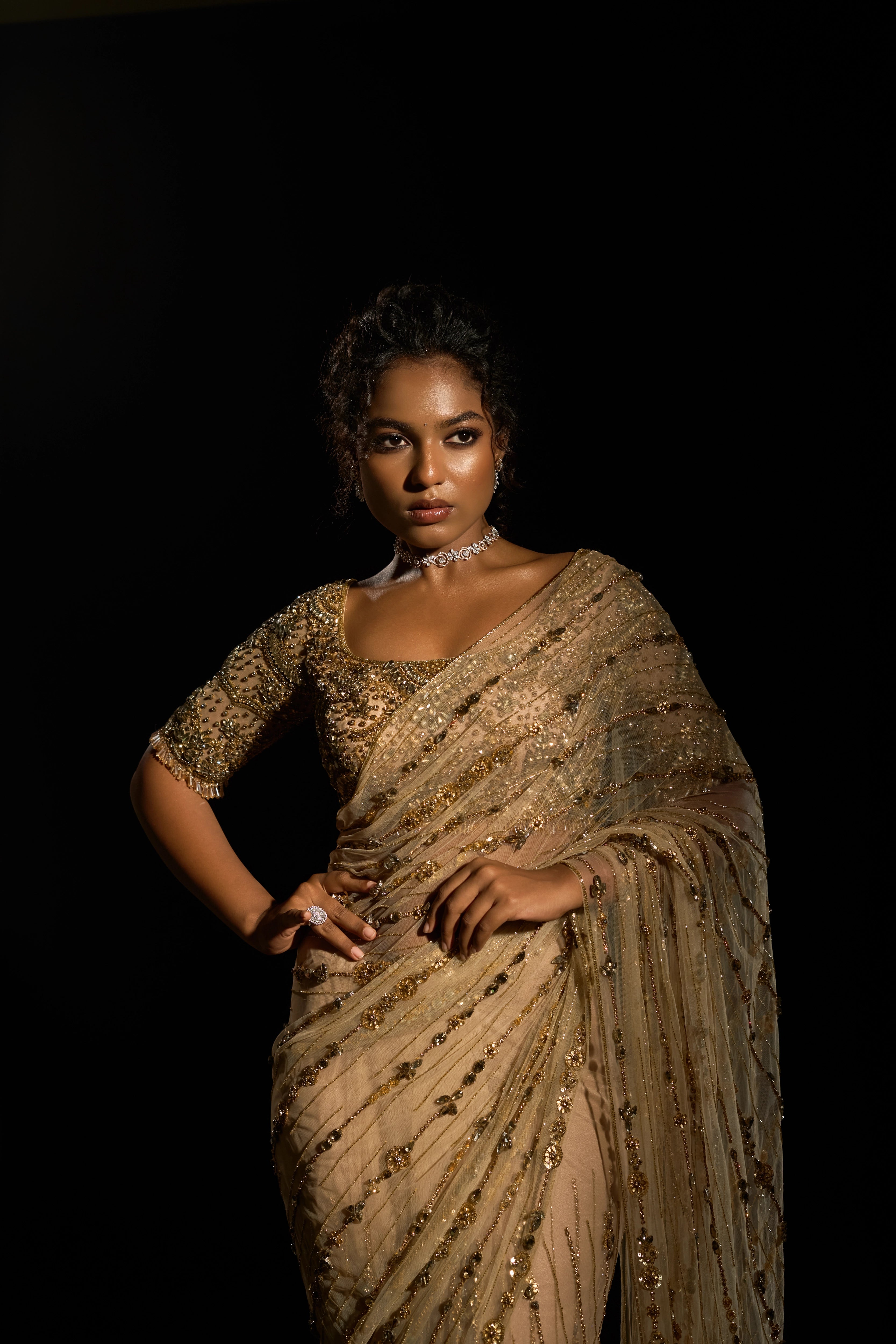 Model Ashika Crystal posing and showcasing front profile in a gold saree set intricately adorned with sequins, rhinestones, crystals and cutdana for "STARDUST" - A/W'25 saree collection by team Archana Karthick.
