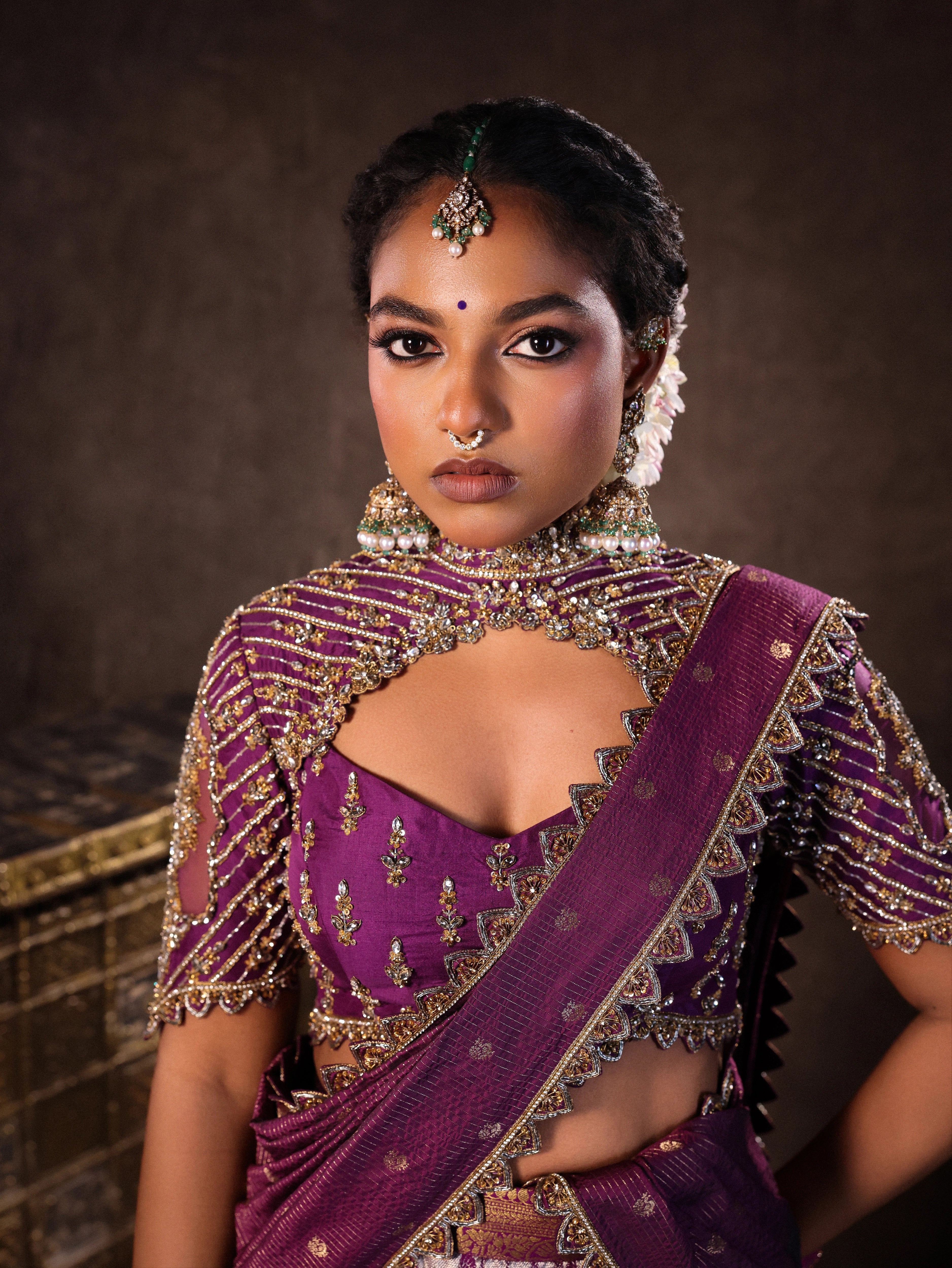 Model Ashika Crystal posing for closeup in a silk half saree set in purple, handcrafted with zardozi, sequins and rhinestones. Team Archana Karthick completed the style with purple glass bangles, a ring, jhumkas, nose ring and a maang tikka.
