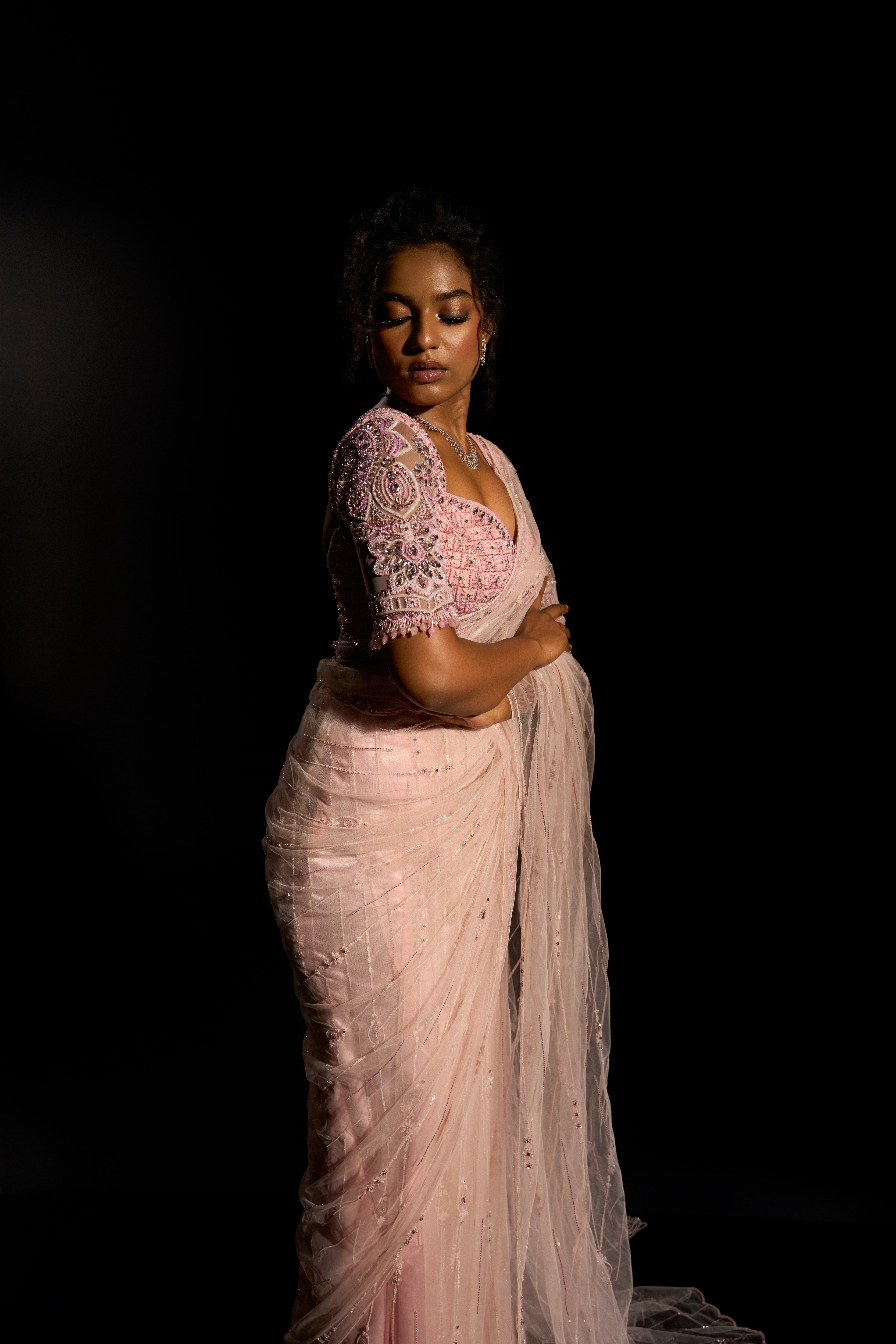 Model Ashika Crystal posing for side profile in a blush pink saree set, intricately adorned with sequins, rhinestones, crystals and cutdana for "STARDUST" - A/W'25 saree collection by team Archana Karthick.