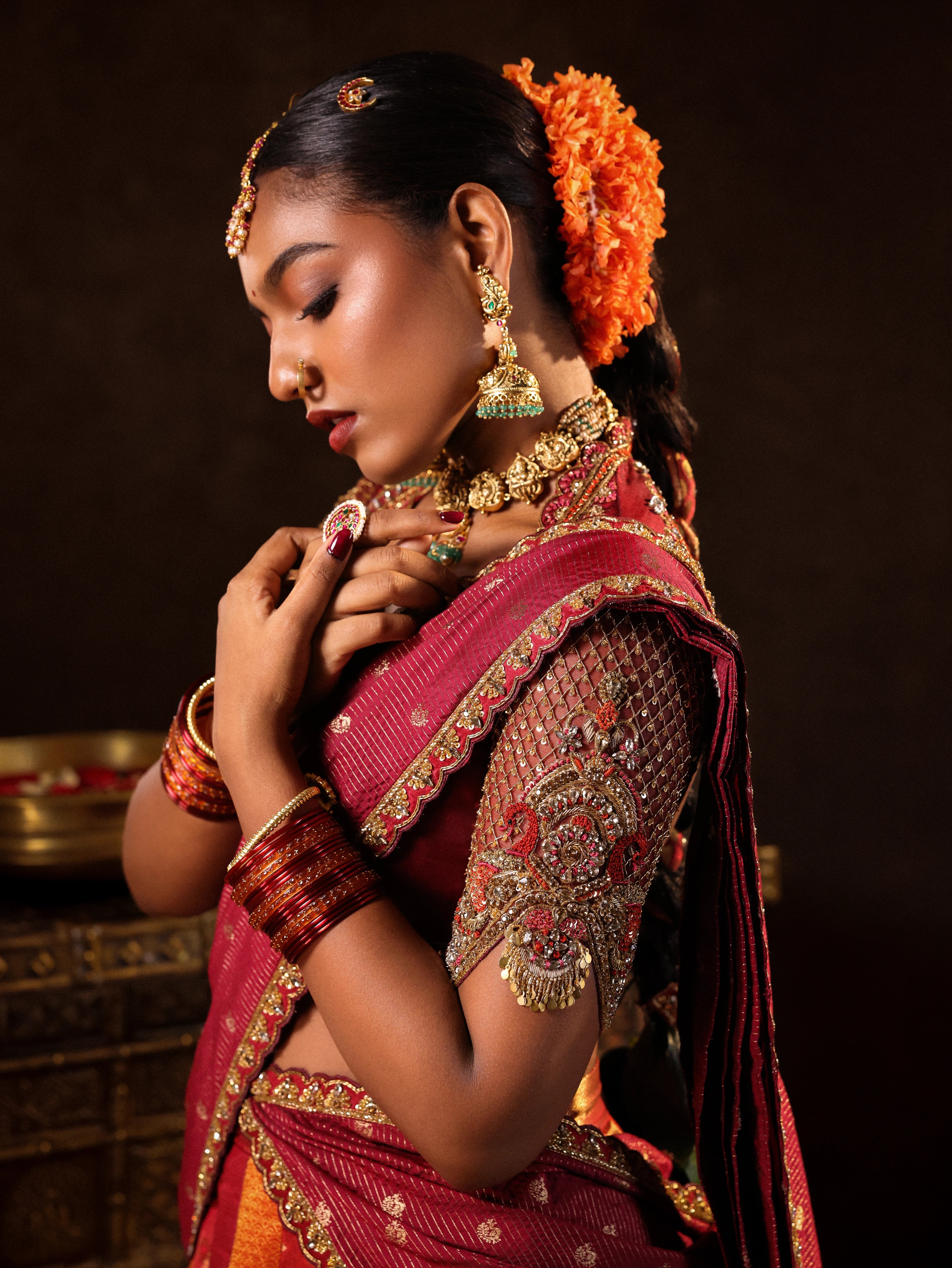 Model Ashika Crystal posing for sleeve detailing in a red and orange silk half saree with a scalloped veil is handrcrafted with sequins, cutdana, resham, stones and exquisite hangings by team Archana Karthick