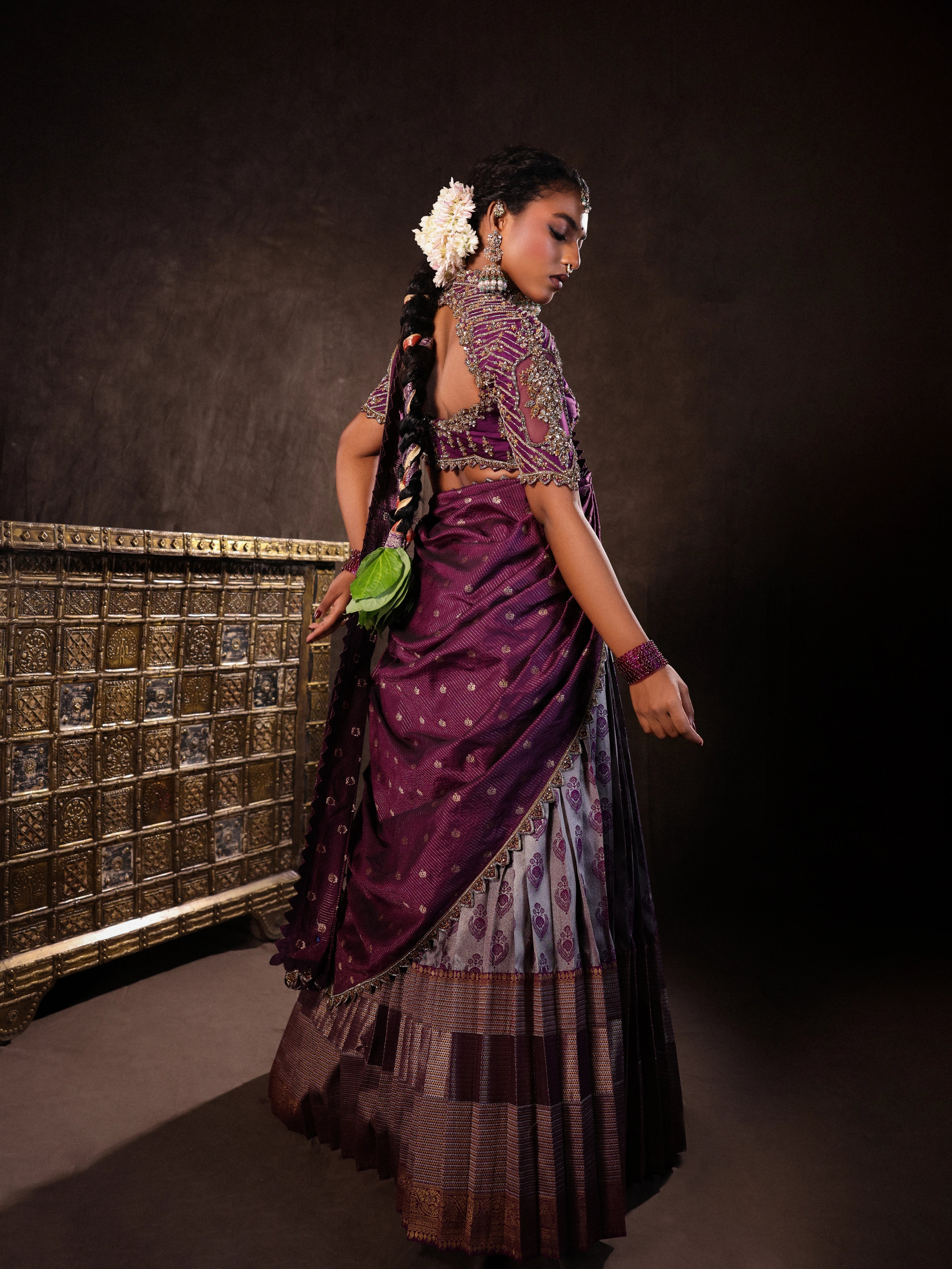 Model Ashika Crystal showcasing back design in a silk half saree set in purple, handcrafted with zardozi, sequins and rhinestones. Team Archana Karthick completed the style with purple glass bangles, a ring, jhumkas, nose ring and a maang tikka.