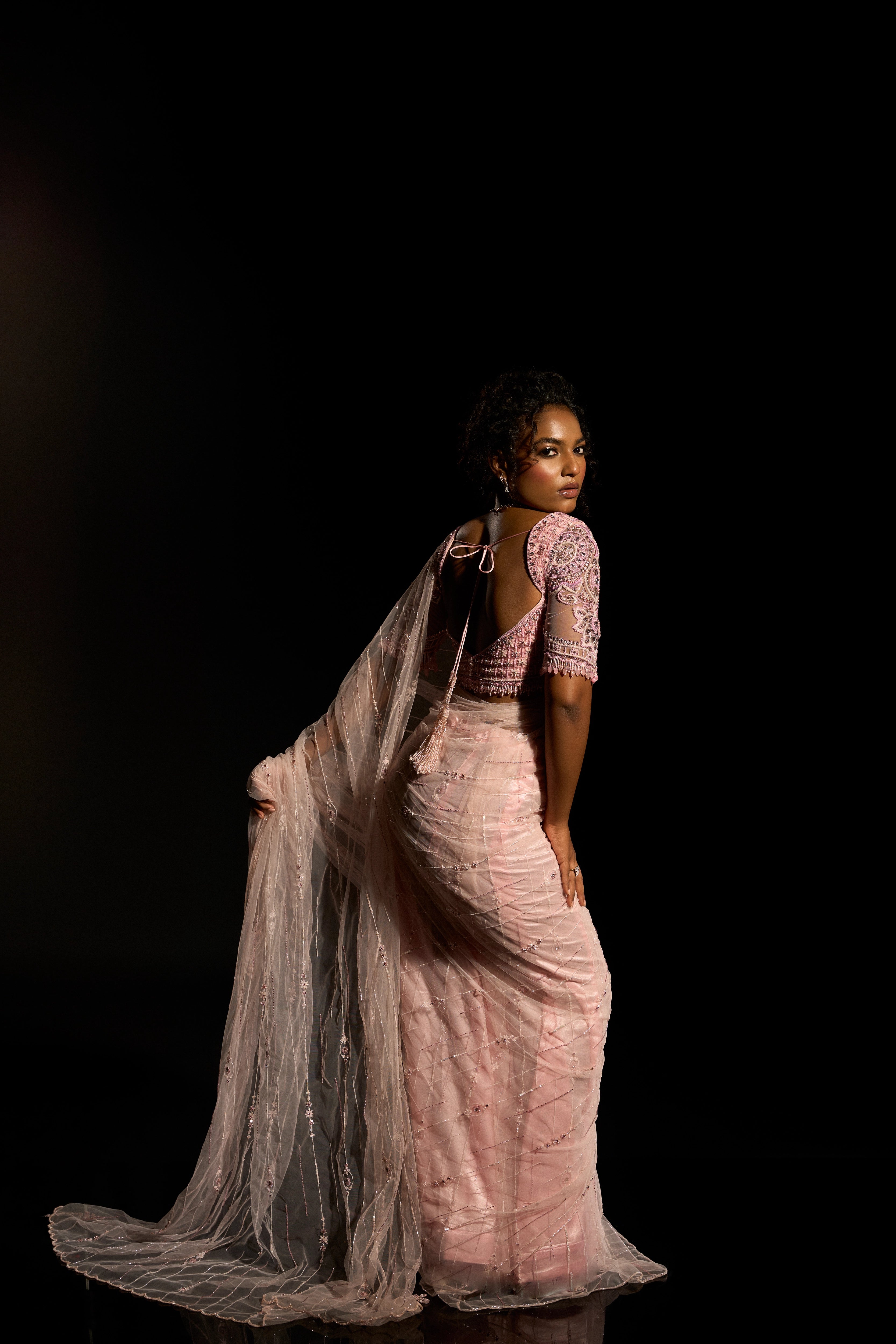 Model Ashika Crystal showcasing back profile in a blush pink saree set, intricately adorned with sequins, rhinestones, crystals and cutdana for "STARDUST" - A/W'25 saree collection by team Archana Karthick.