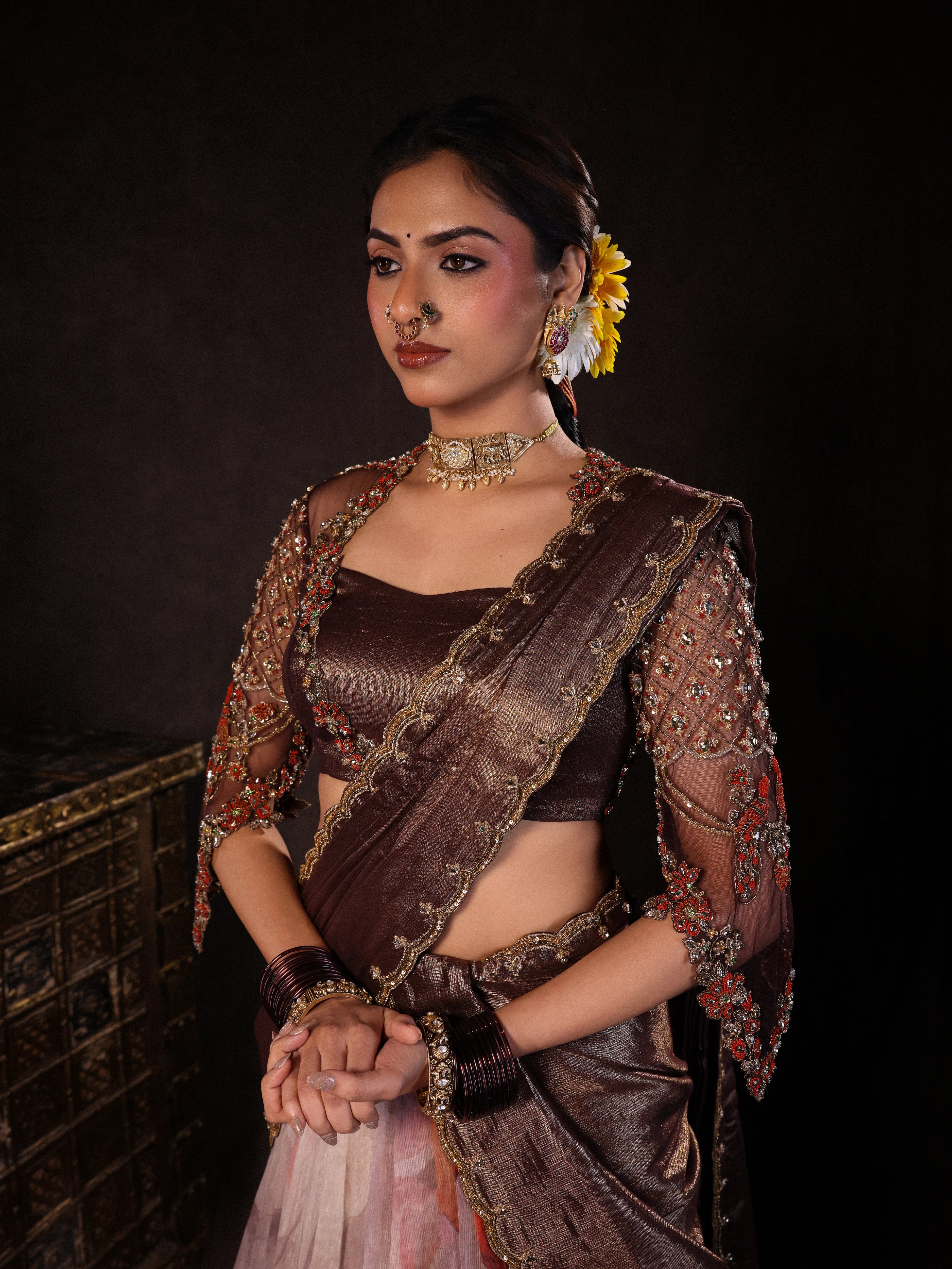 Model Dr Sree Advaita posing for front and side profile in a brown & printed ivory silk half saree set handcrafted with zardozi, resham, cutdana, sequins & rhinestones. Team Archana Karthick completed the style with brown glass bangles, a ring, jhumkas, nose ring and a maang tikka.