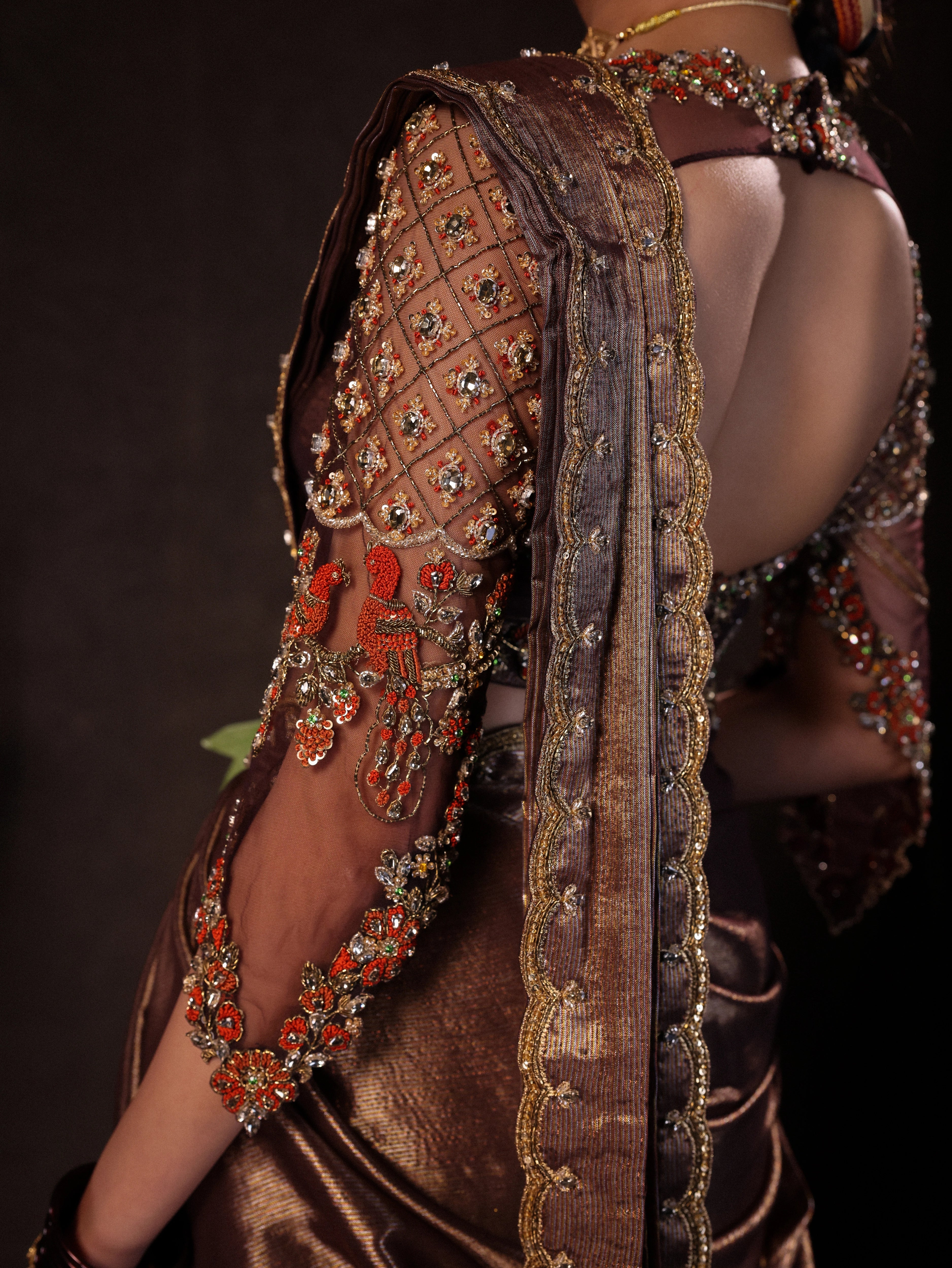 Model Dr Sree Advaita posing for sleeve detailing in a brown & printed ivory silk half saree set handcrafted with zardozi, resham, cutdana, sequins & rhinestones. Team Archana Karthick completed the style with brown glass bangles, a ring, jhumkas, nose ring and a maang tikka.