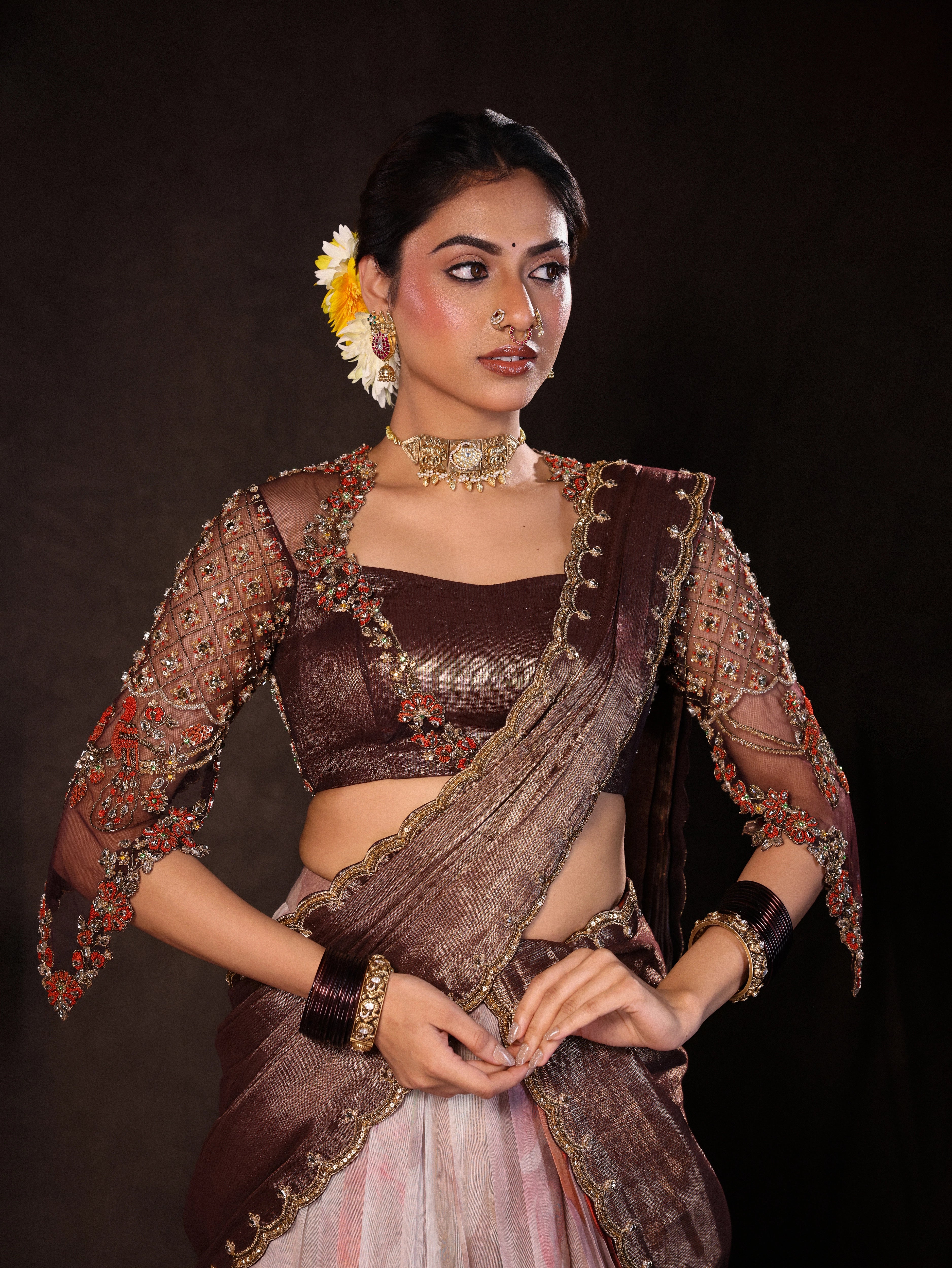 Model Dr Sree Advaita posing in a brown & printed ivory silk half saree set handcrafted with zardozi, resham, cutdana, sequins & rhinestones. Team Archana Karthick completed the style with brown glass bangles, a ring, jhumkas, nose ring and a maang tikka.